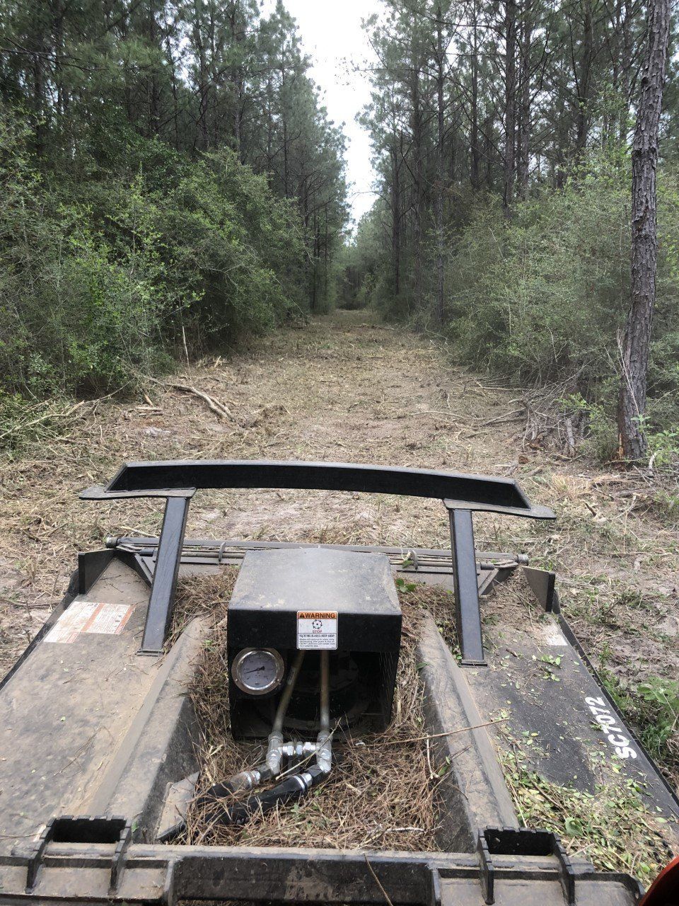 A tractor is driving down a dirt road in the woods