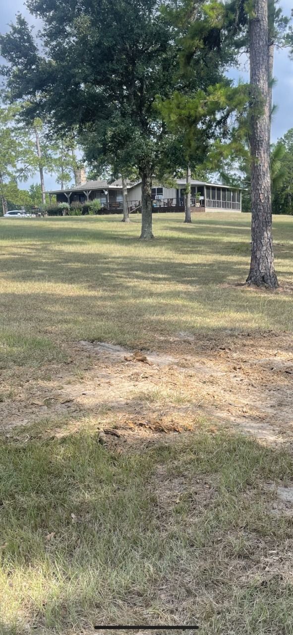 A large grassy field with trees and a house in the background.