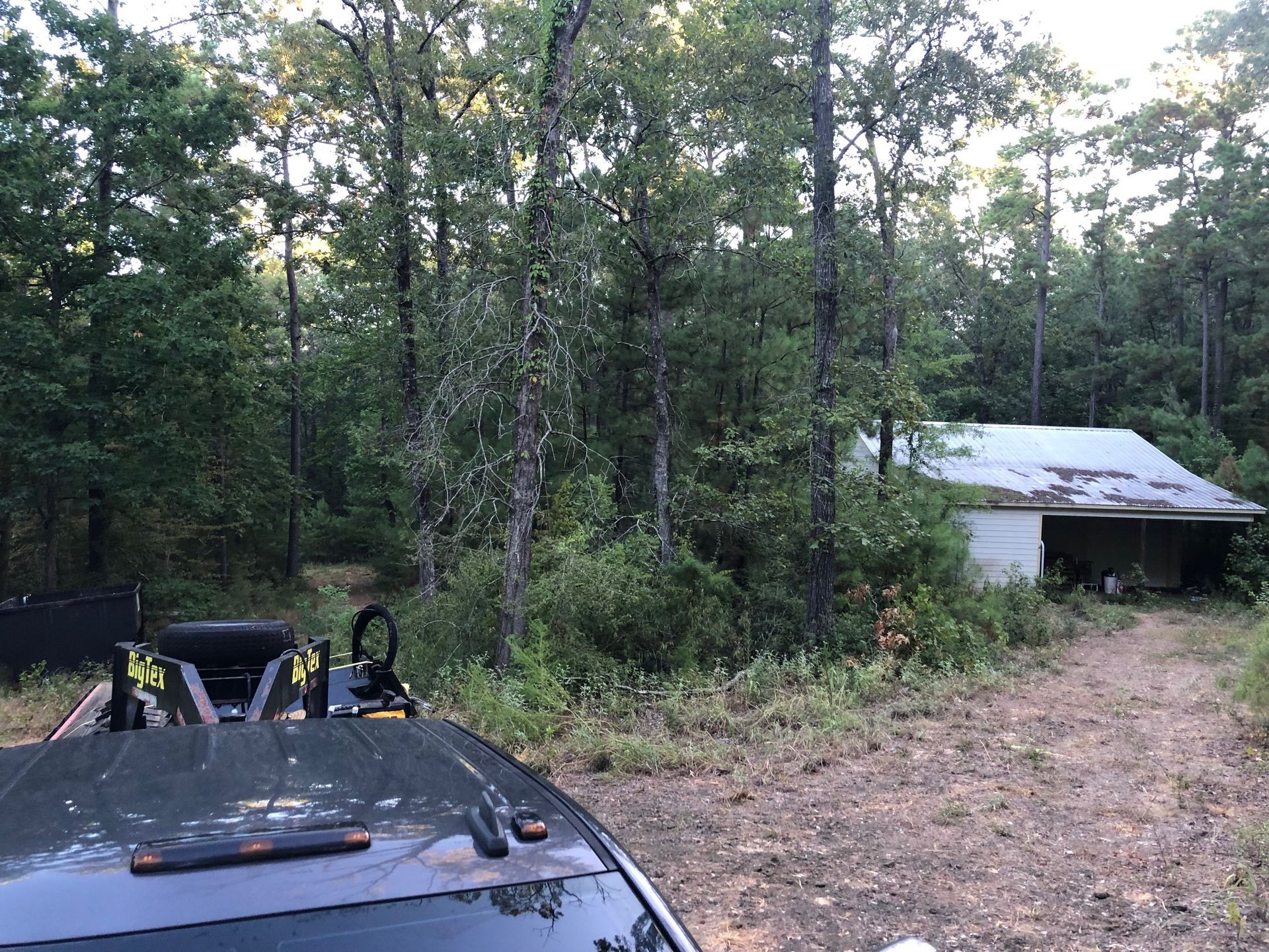A car is parked in front of a house in the woods.