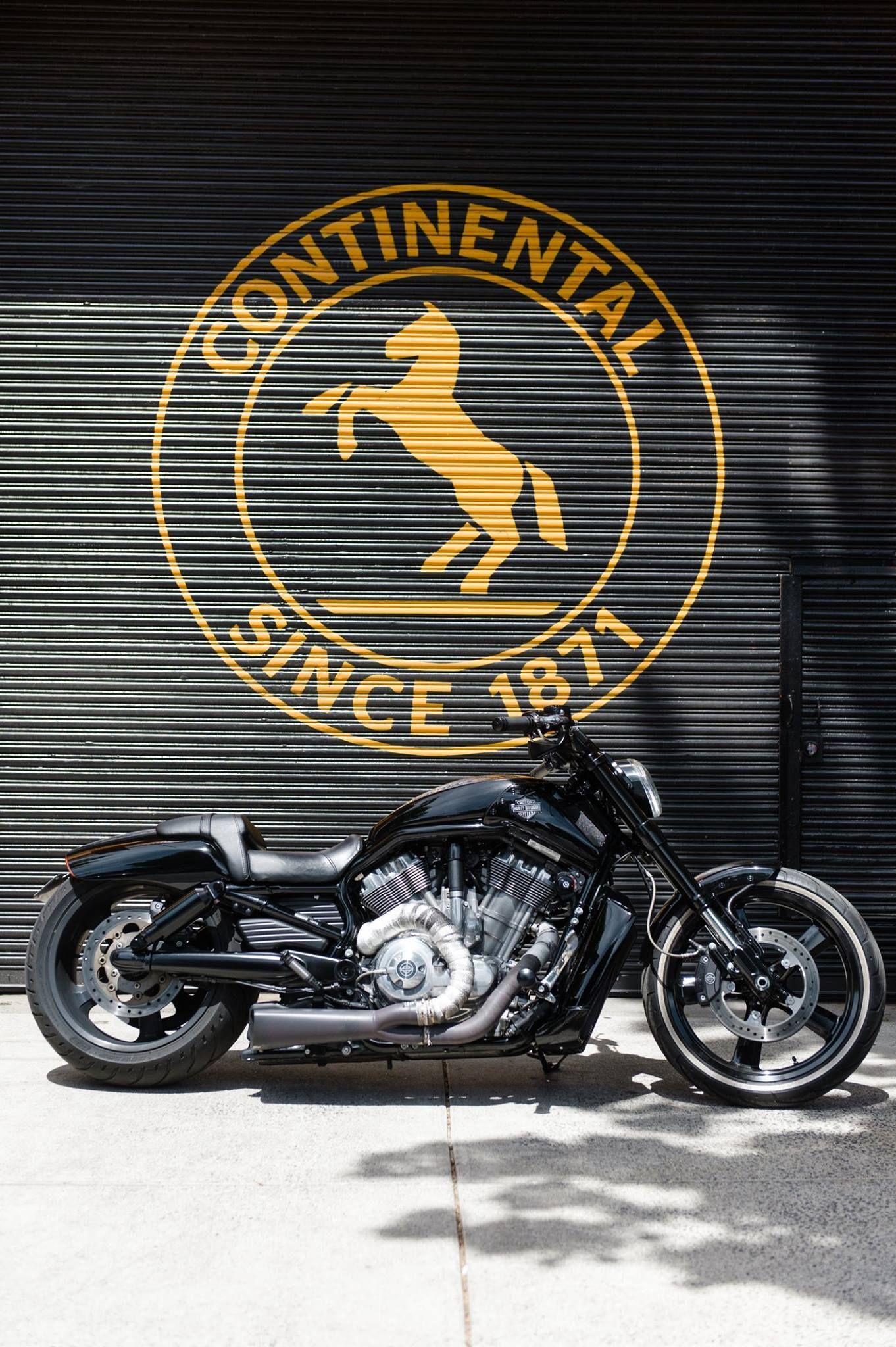 Black motorcycle in front of a Continental Tires logo on a metal shutter.