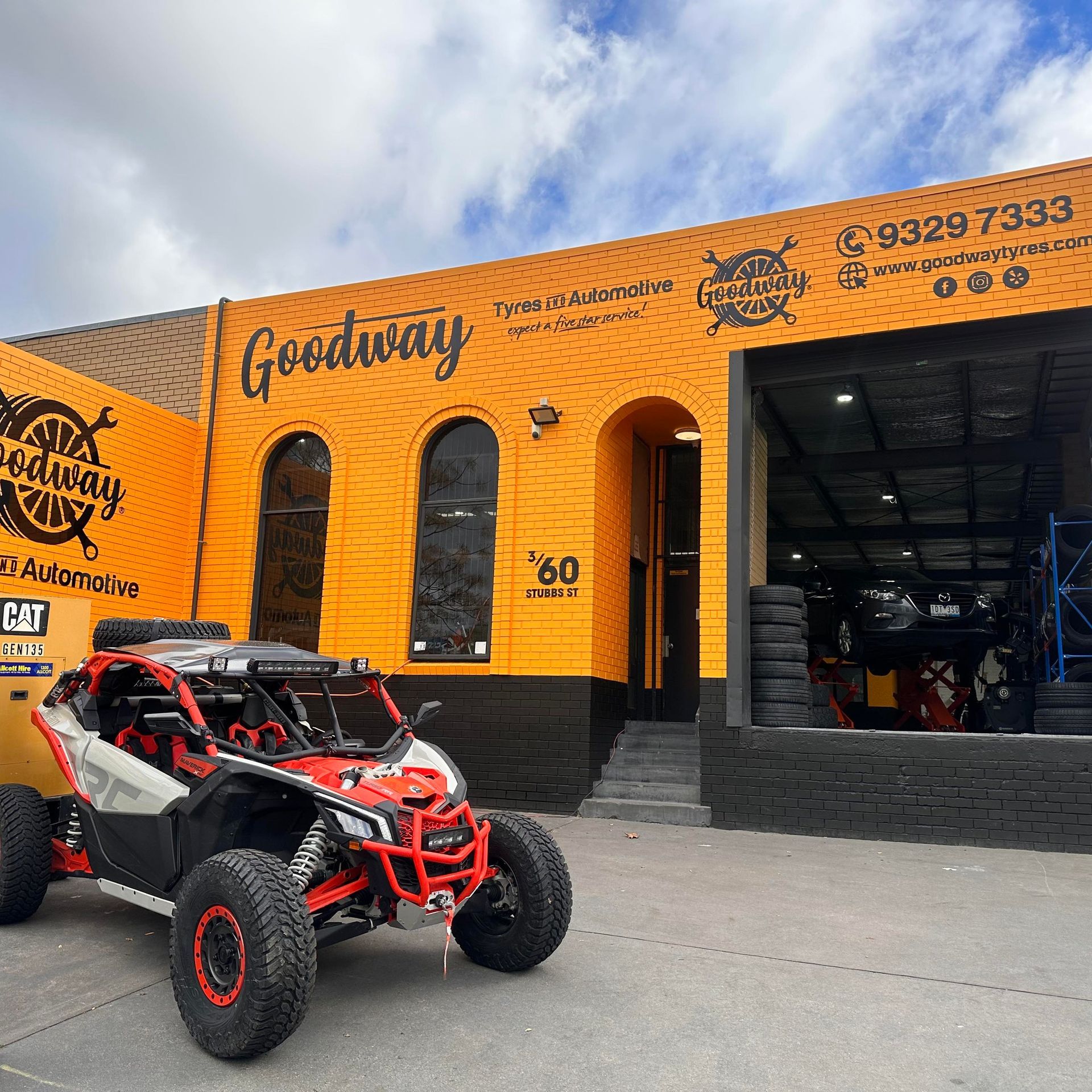Red and white off-road vehicle parked outside an orange Goodway shop.