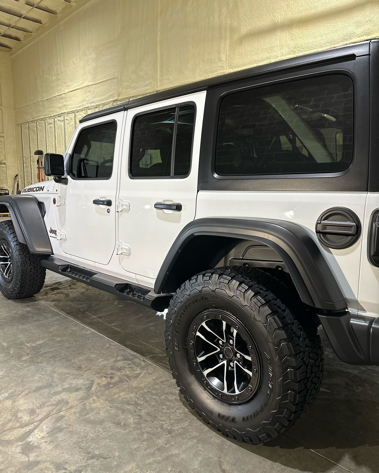 A white jeep wrangler is parked in a garage.