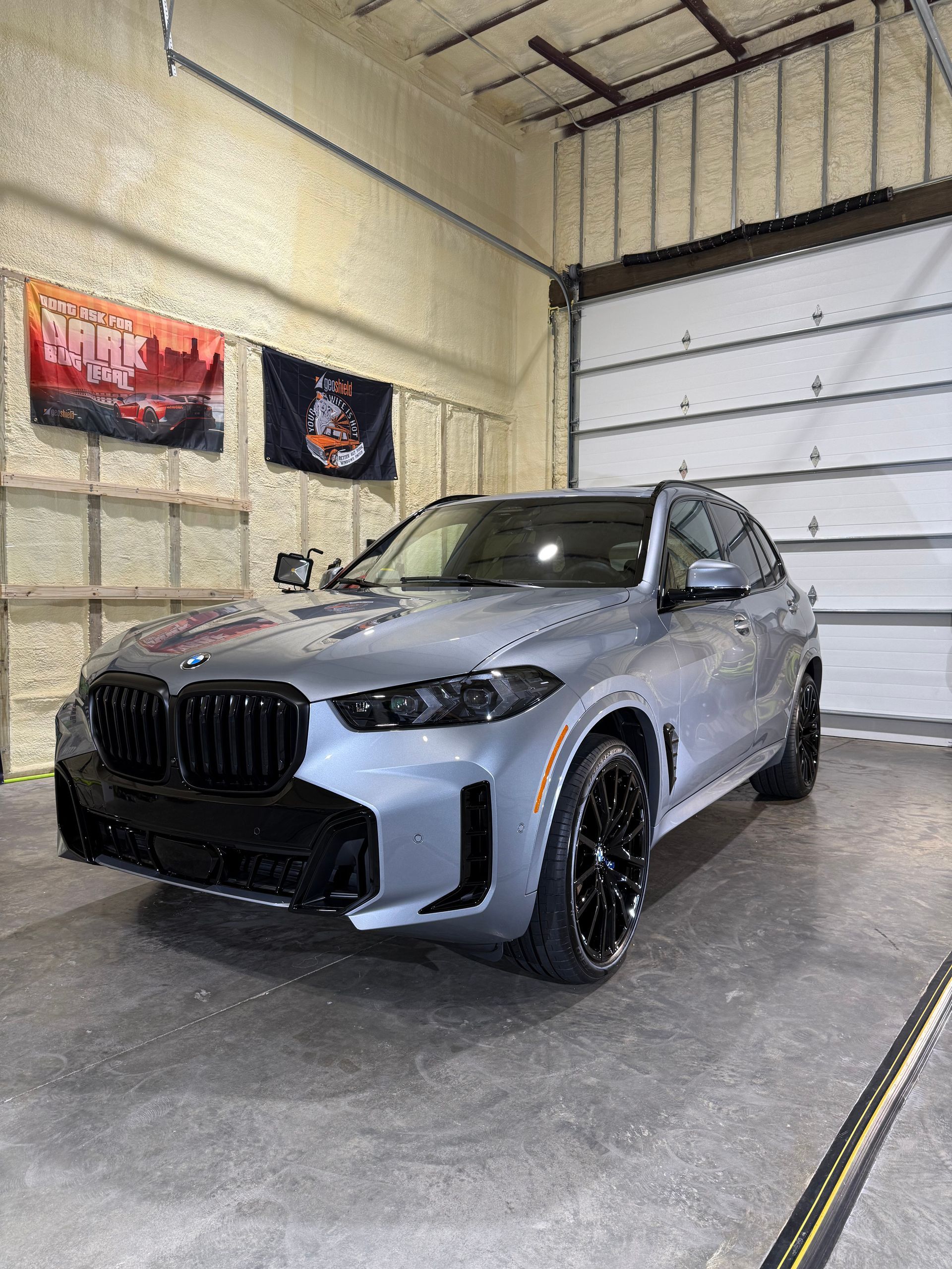 A bmw x3 is parked in a garage next to a garage door.