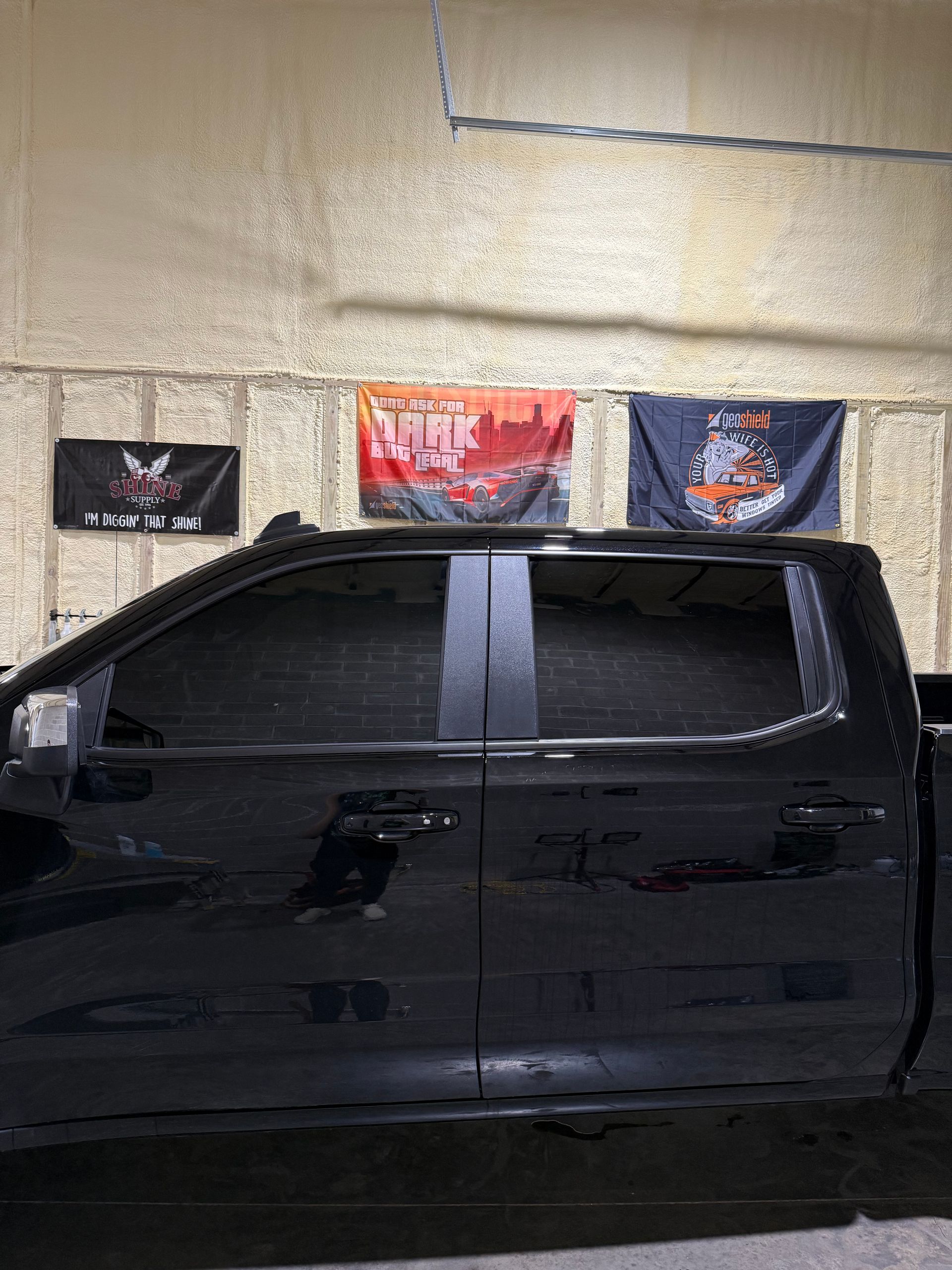 A black truck is parked in a garage with flags on the wall.