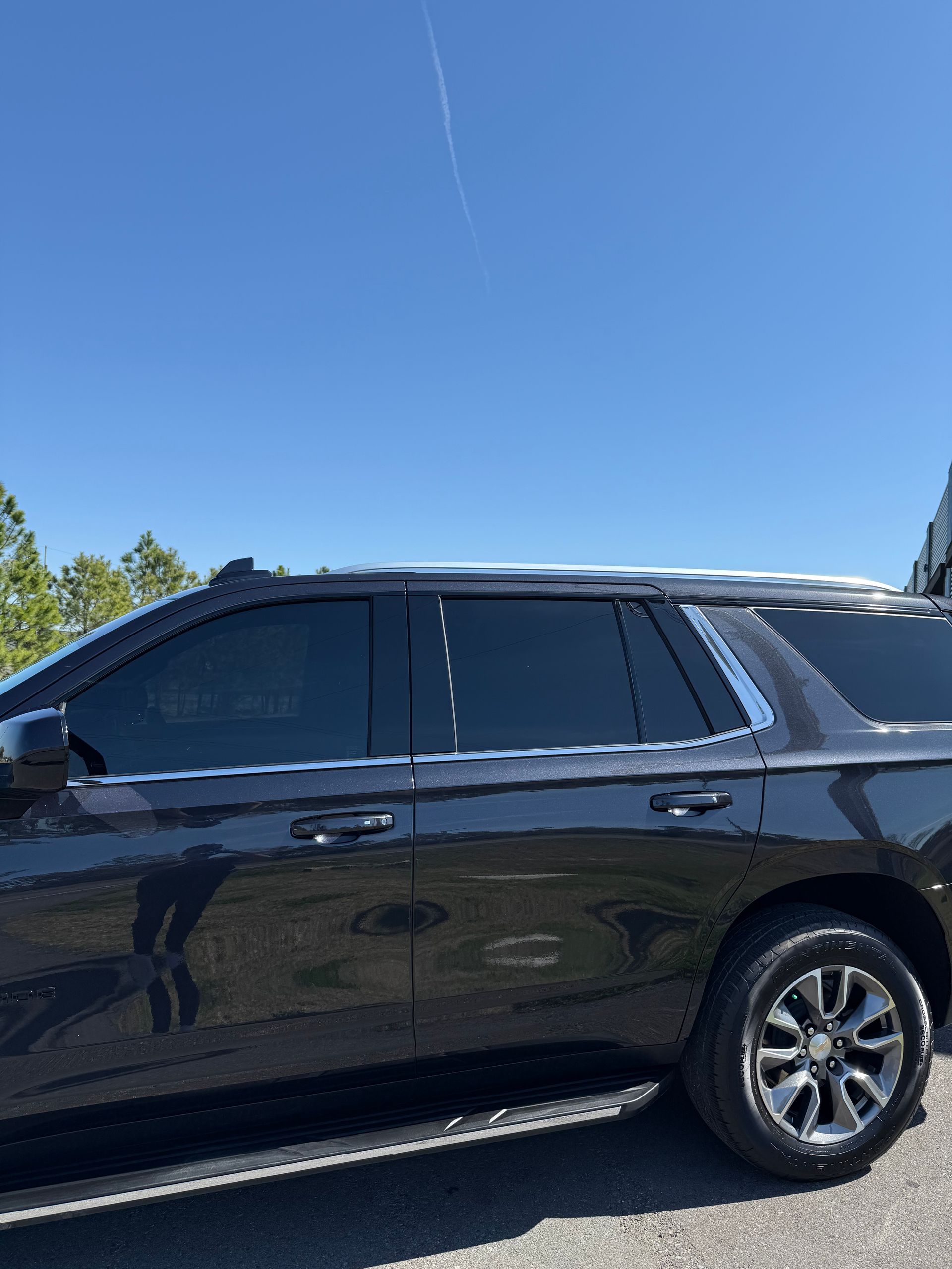 A black suv is parked on the side of the road on a sunny day.
