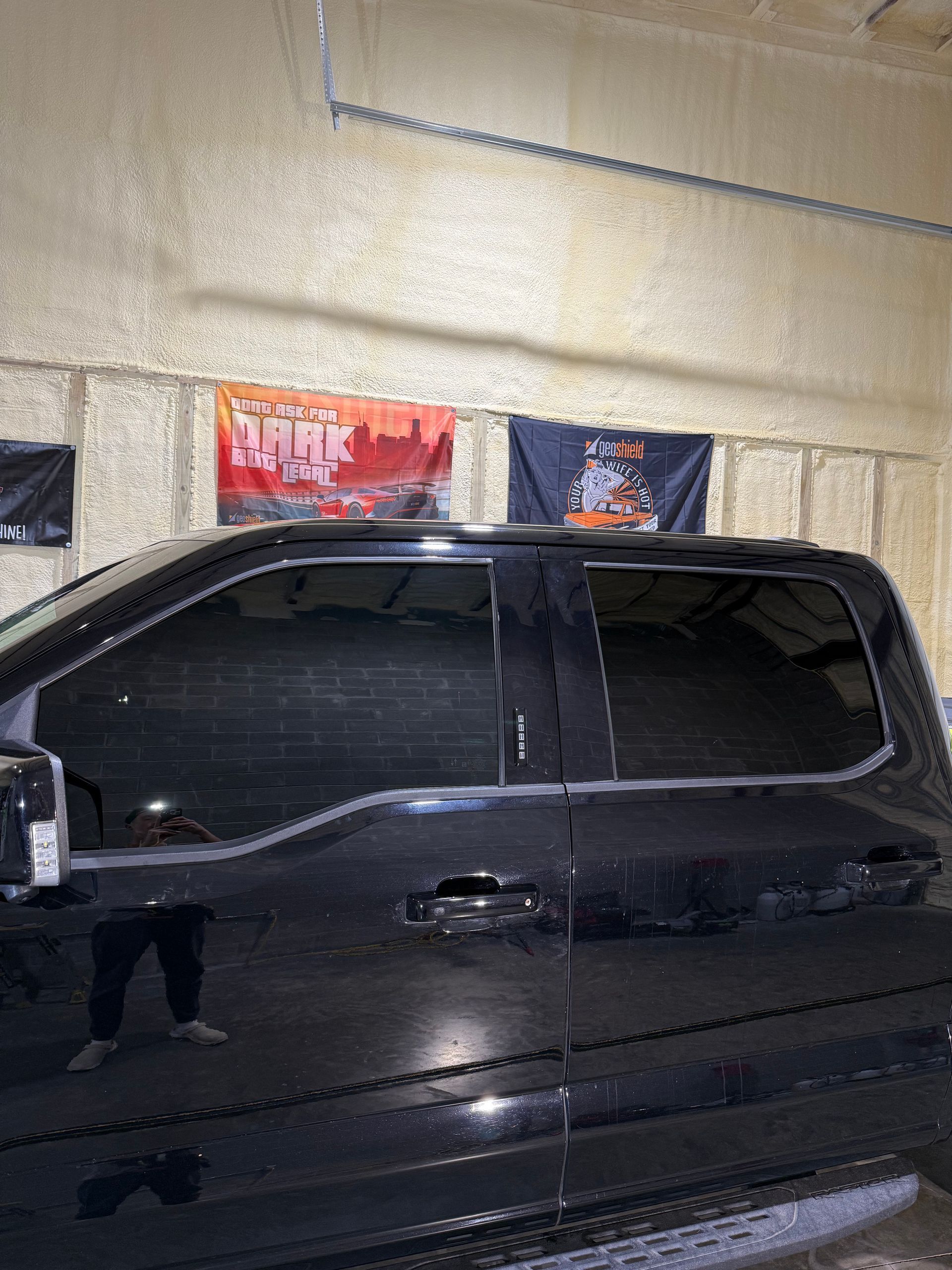 A black truck is parked in a garage with flags on the wall.