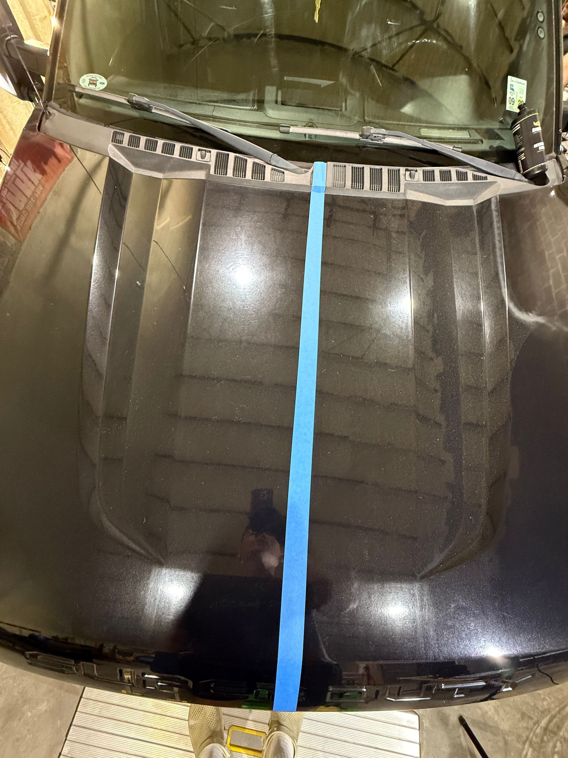 A black car with a blue tape on the hood