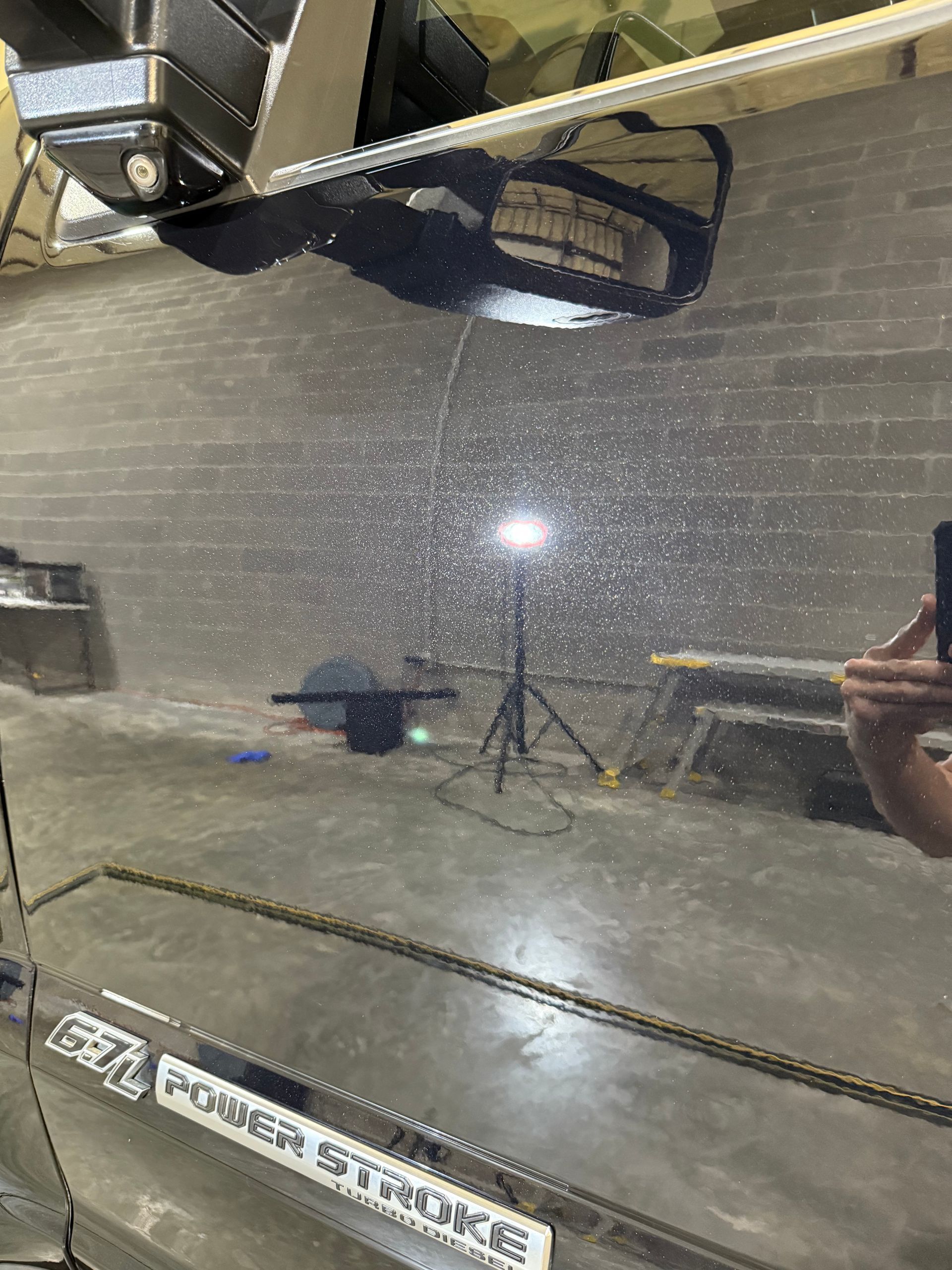 A person is taking a picture of a car in a garage.