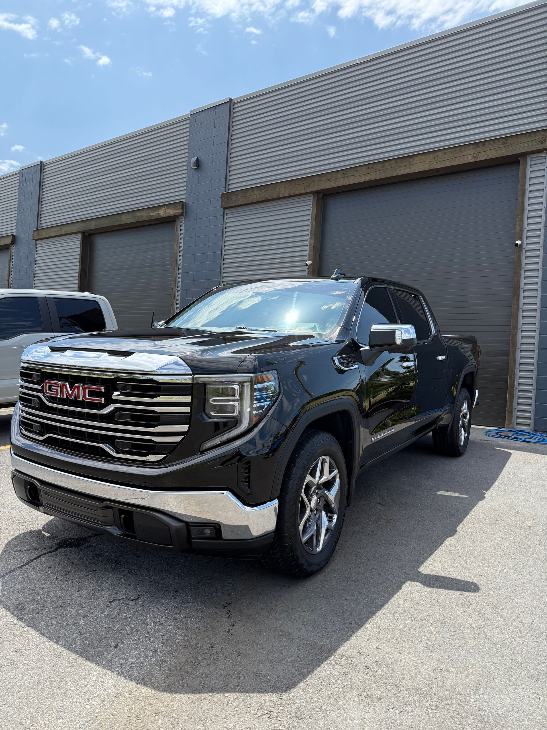 A black gmc truck is parked in front of a building.