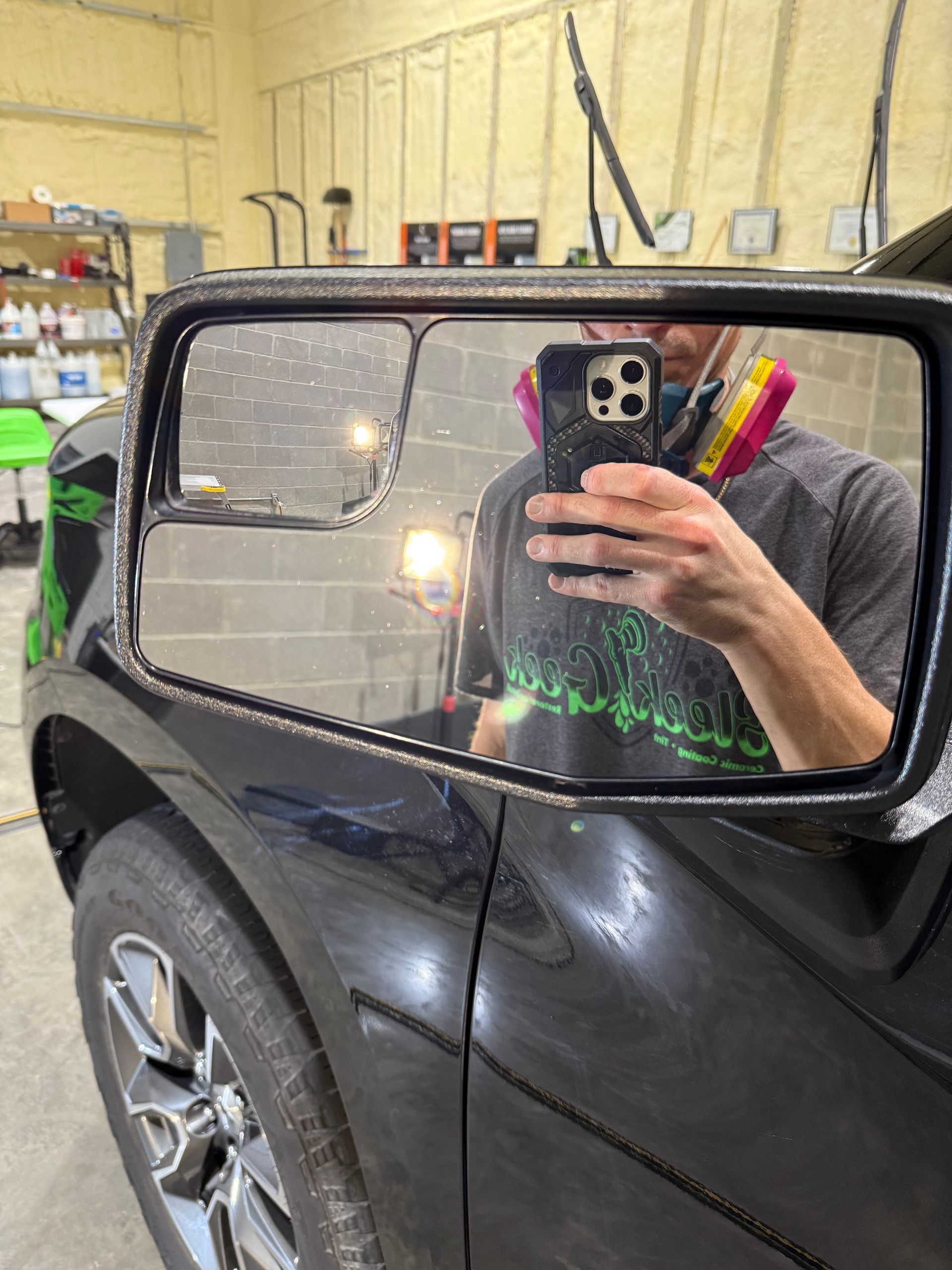 A man is taking a selfie in the side view mirror of a car.