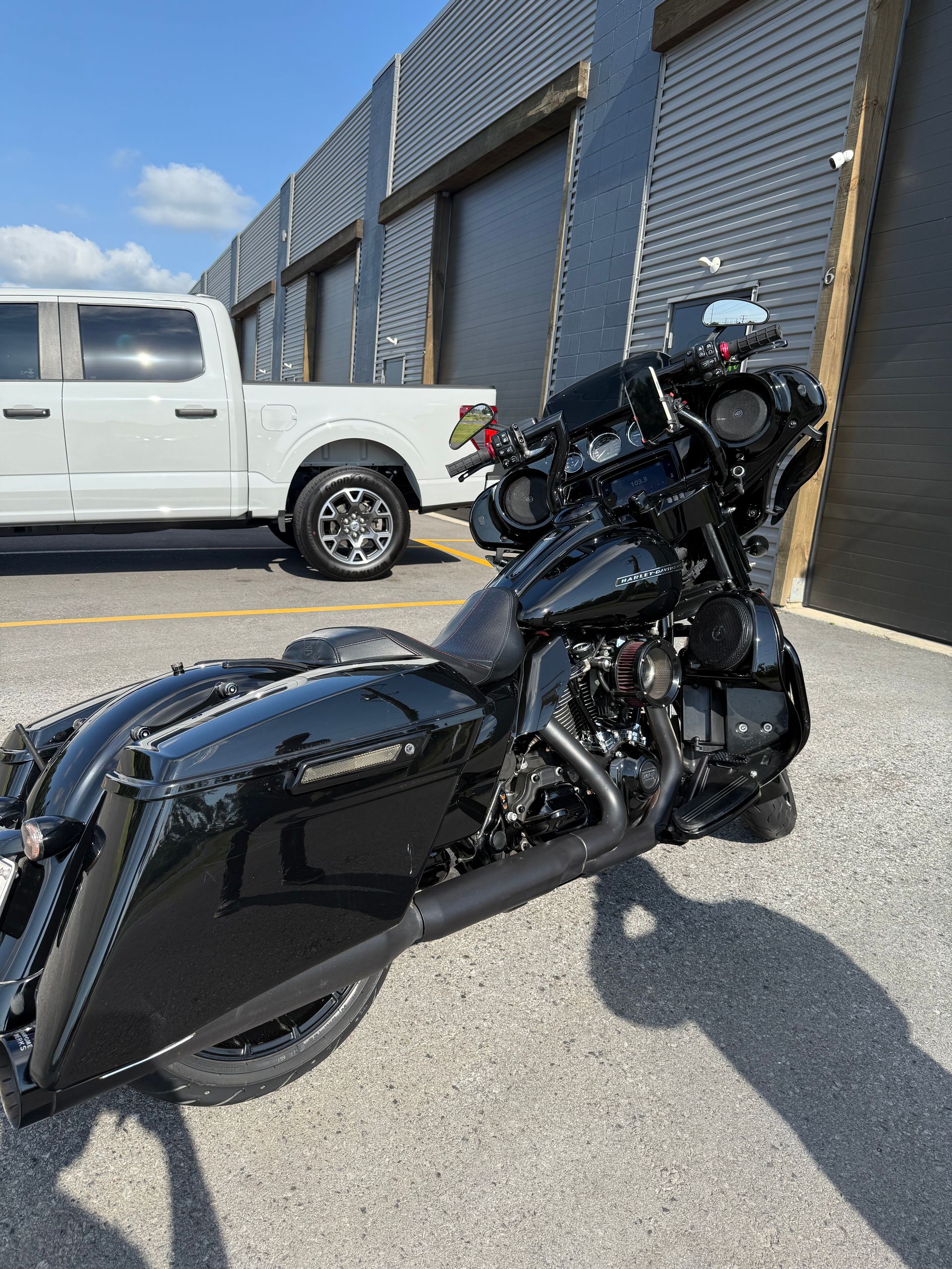 A black motorcycle is parked in front of a white truck.