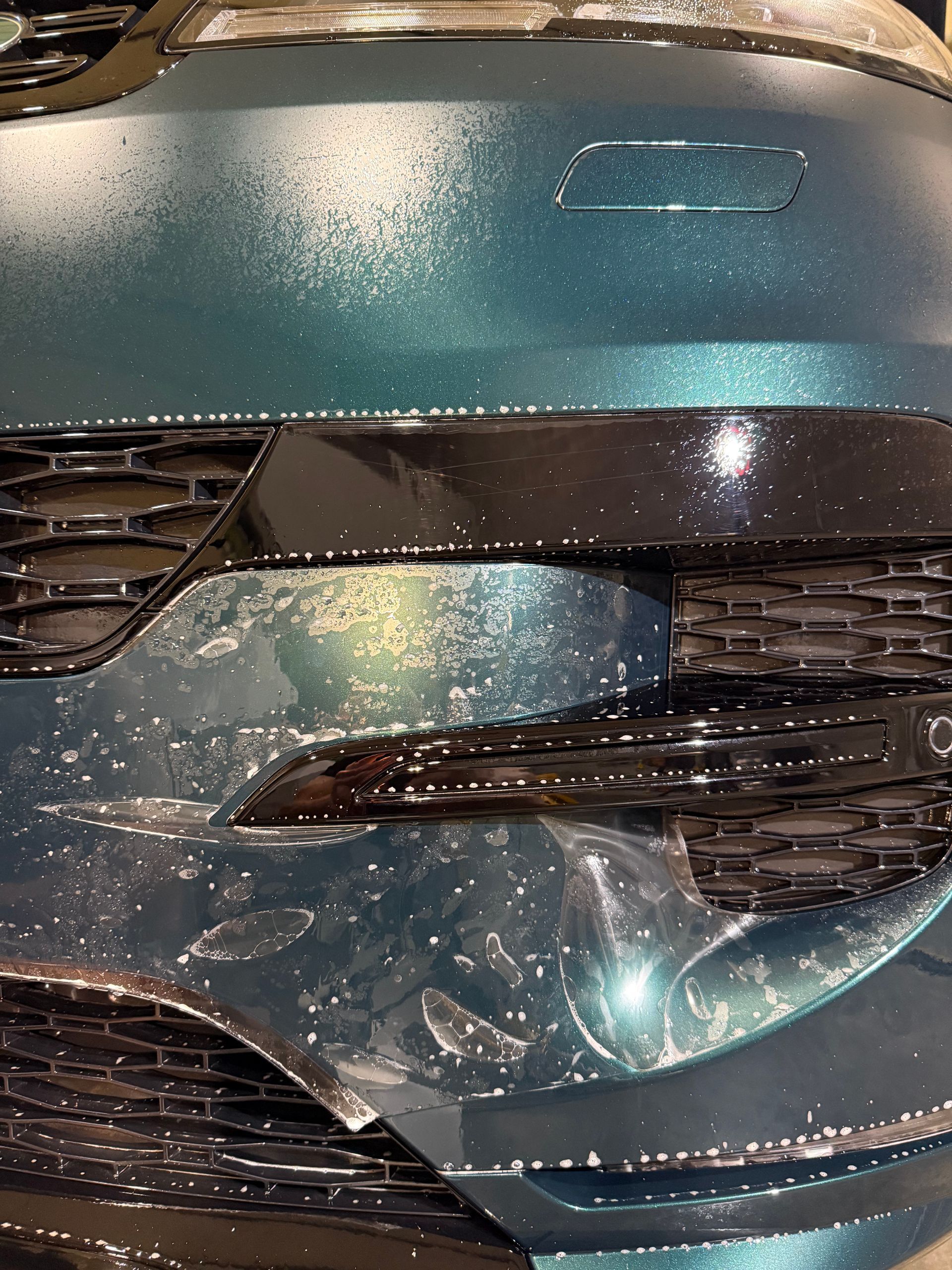 The front of a car is wrapped in plastic.