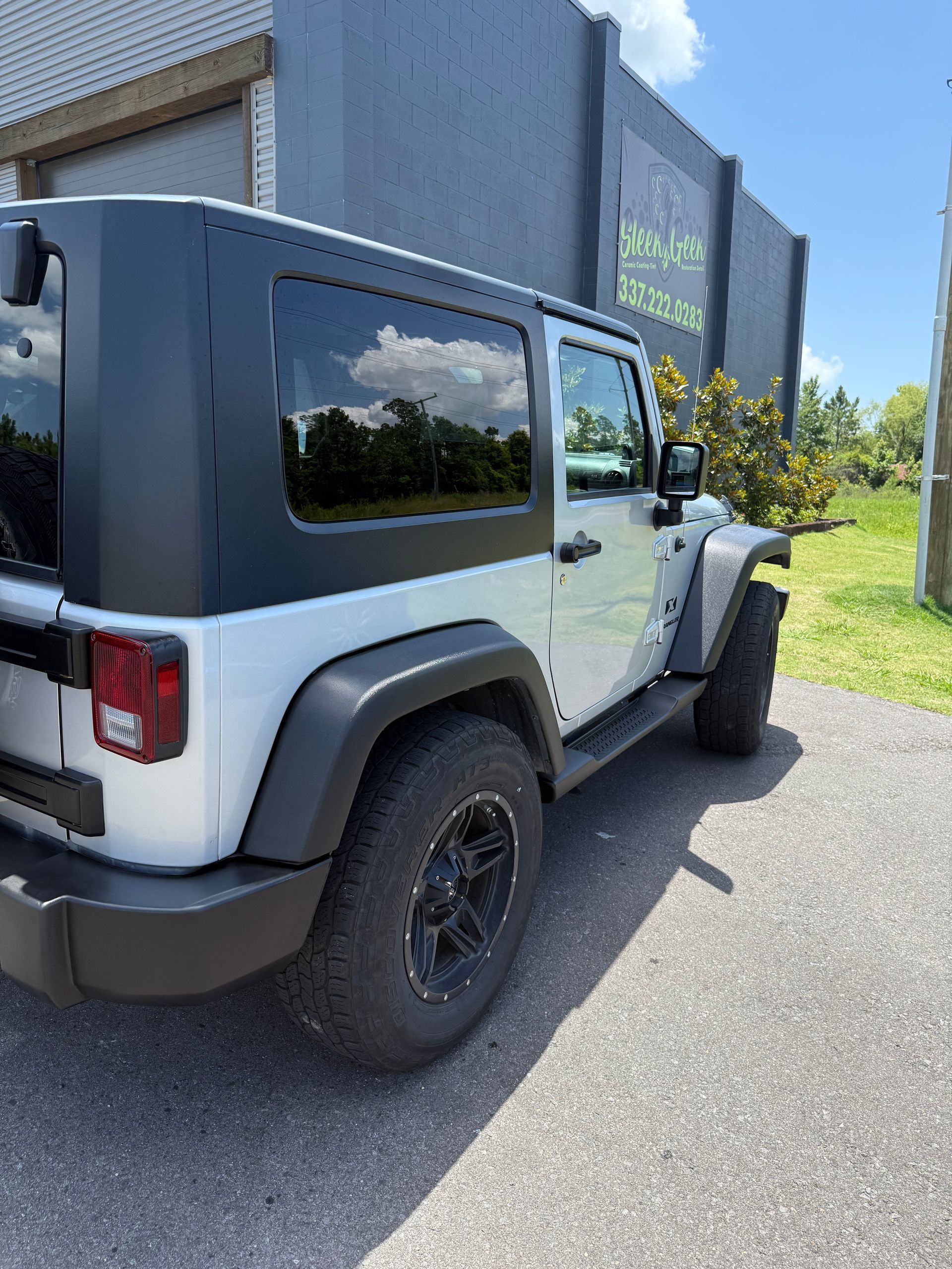 A white jeep is parked in front of a building.