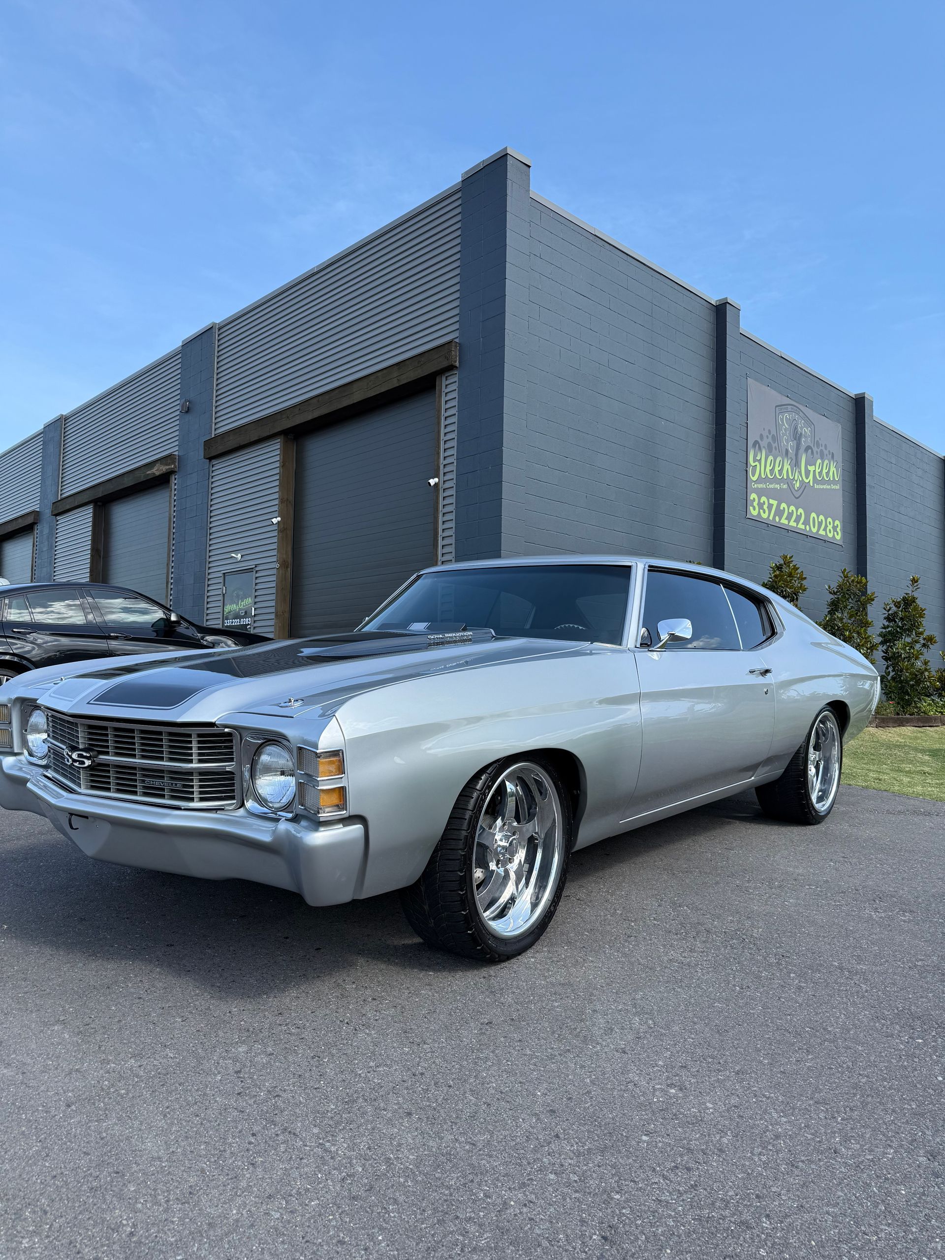A silver car is parked in front of a building.