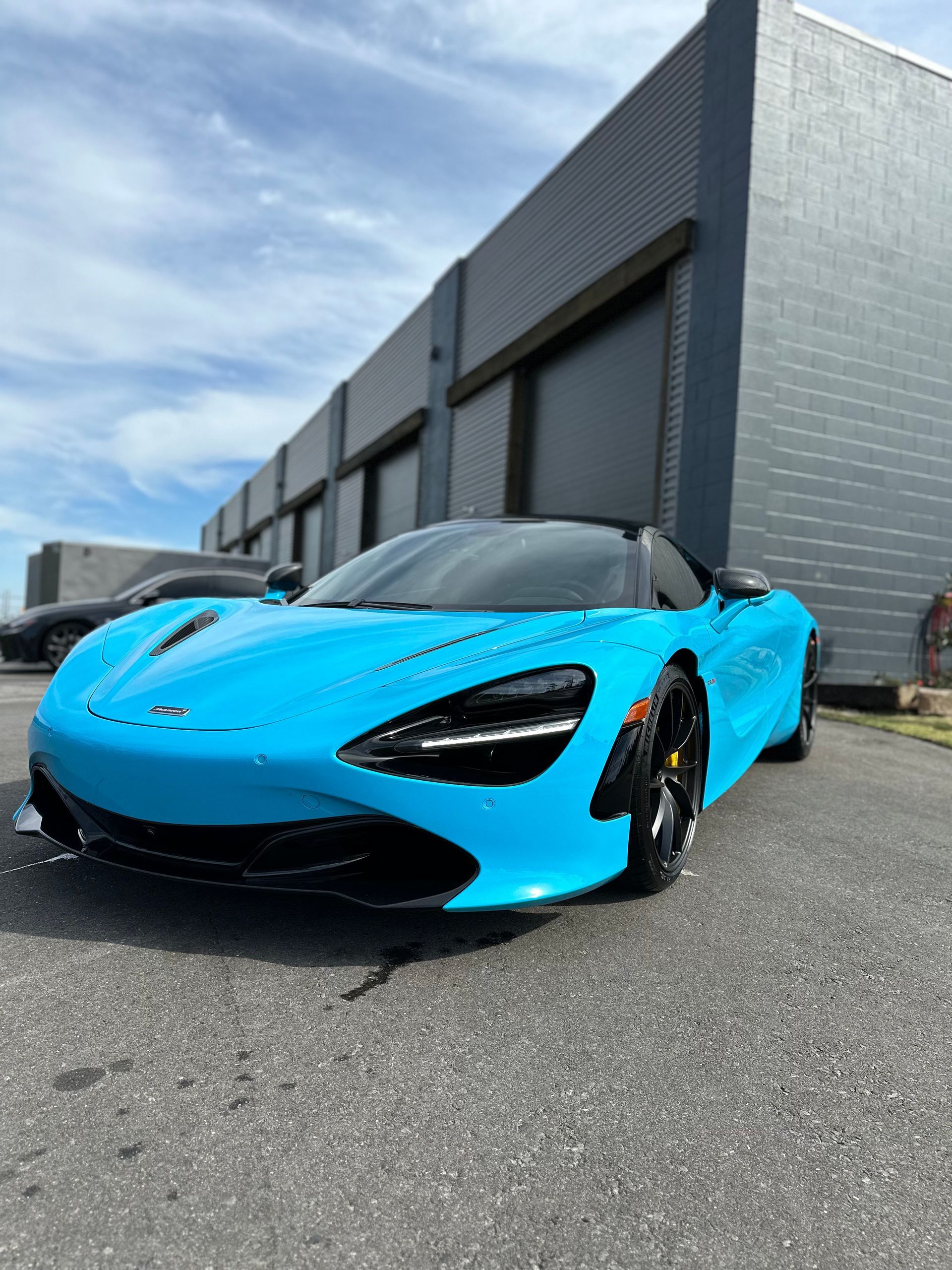 A blue sports car is parked in front of a building.