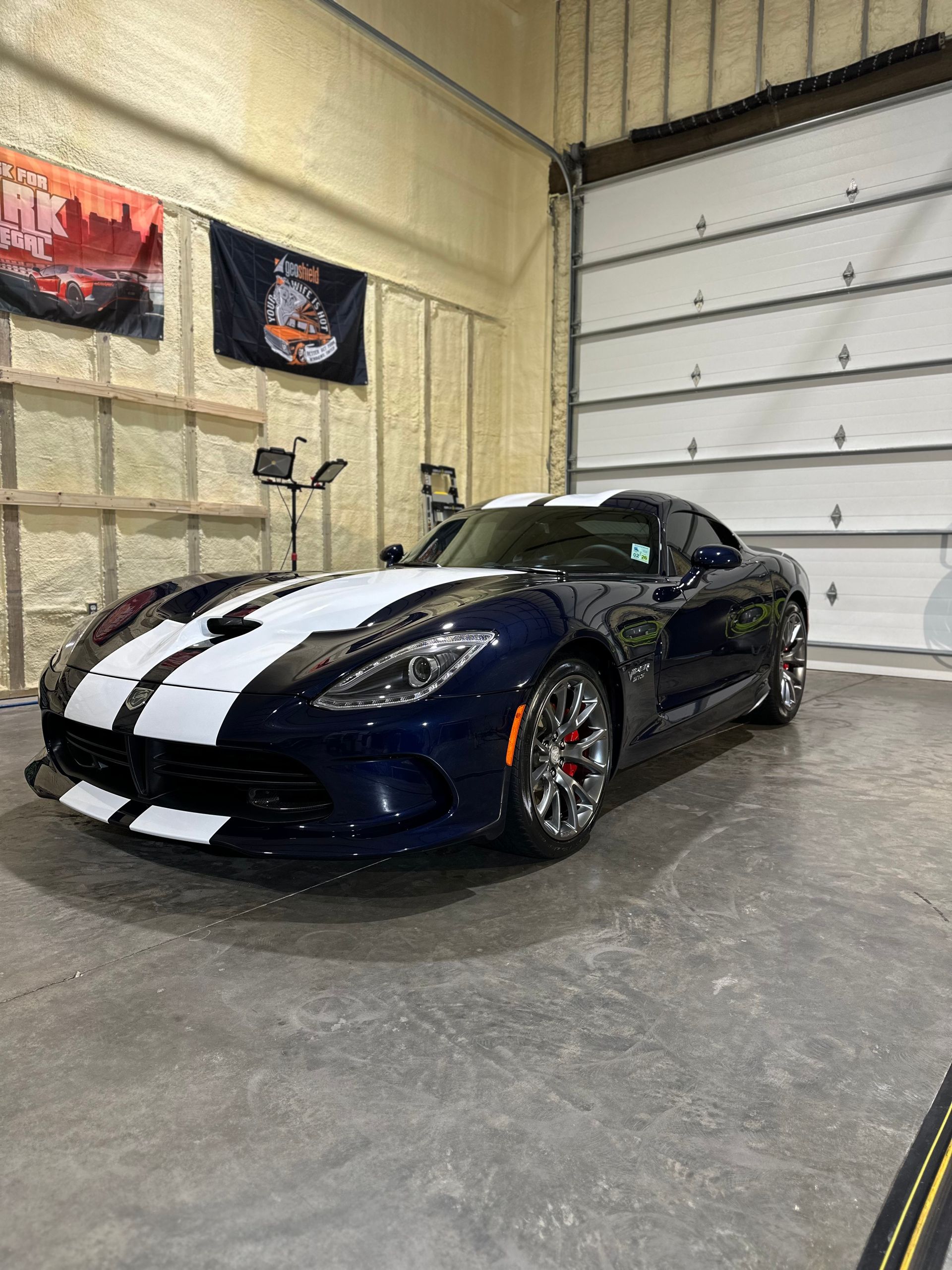 A blue and white dodge viper is parked in a garage.