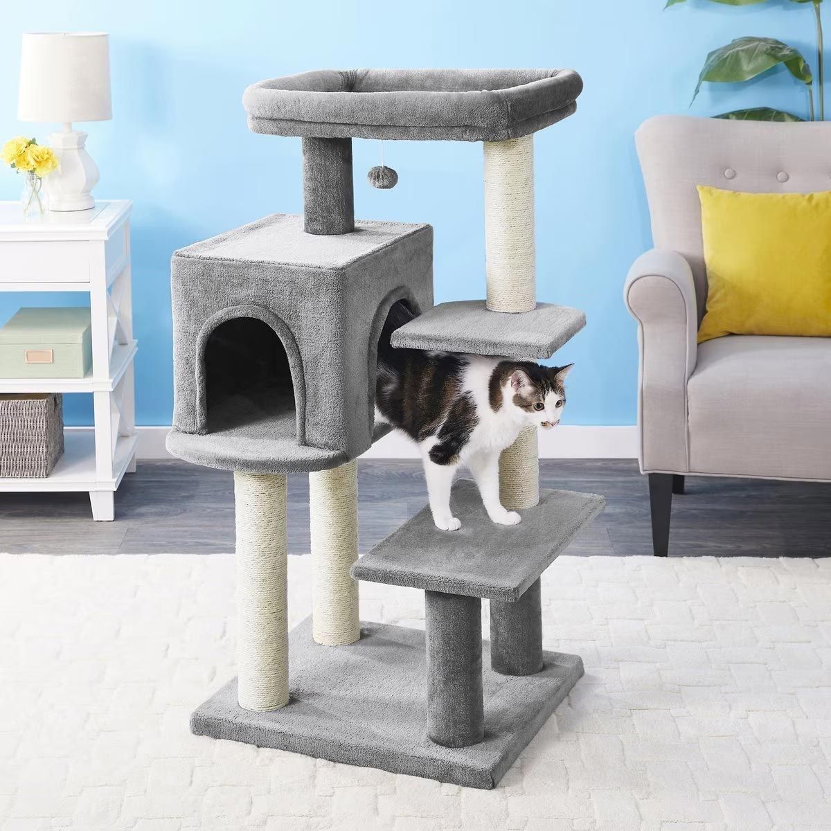 a cat is standing on a cat tree in a living room
