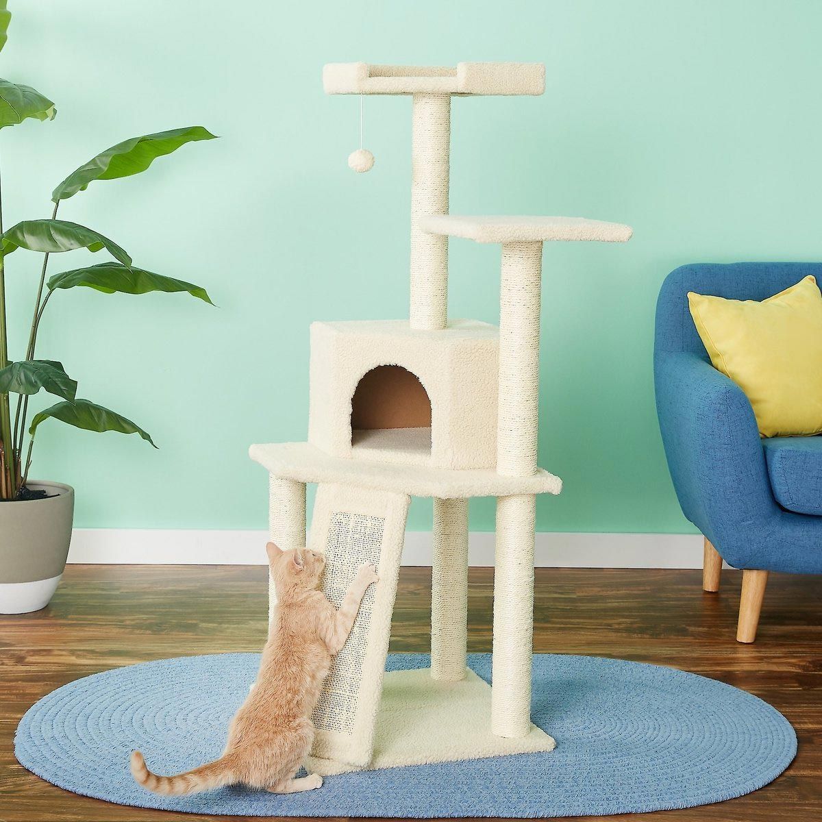 a cat is playing on a cat tree in a living room .