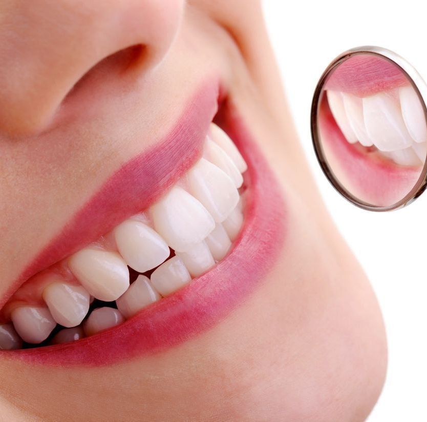 A close up of a woman 's mouth with a mirror showing her teeth