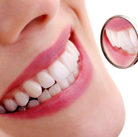 A close up of a woman 's mouth with a mirror showing her teeth