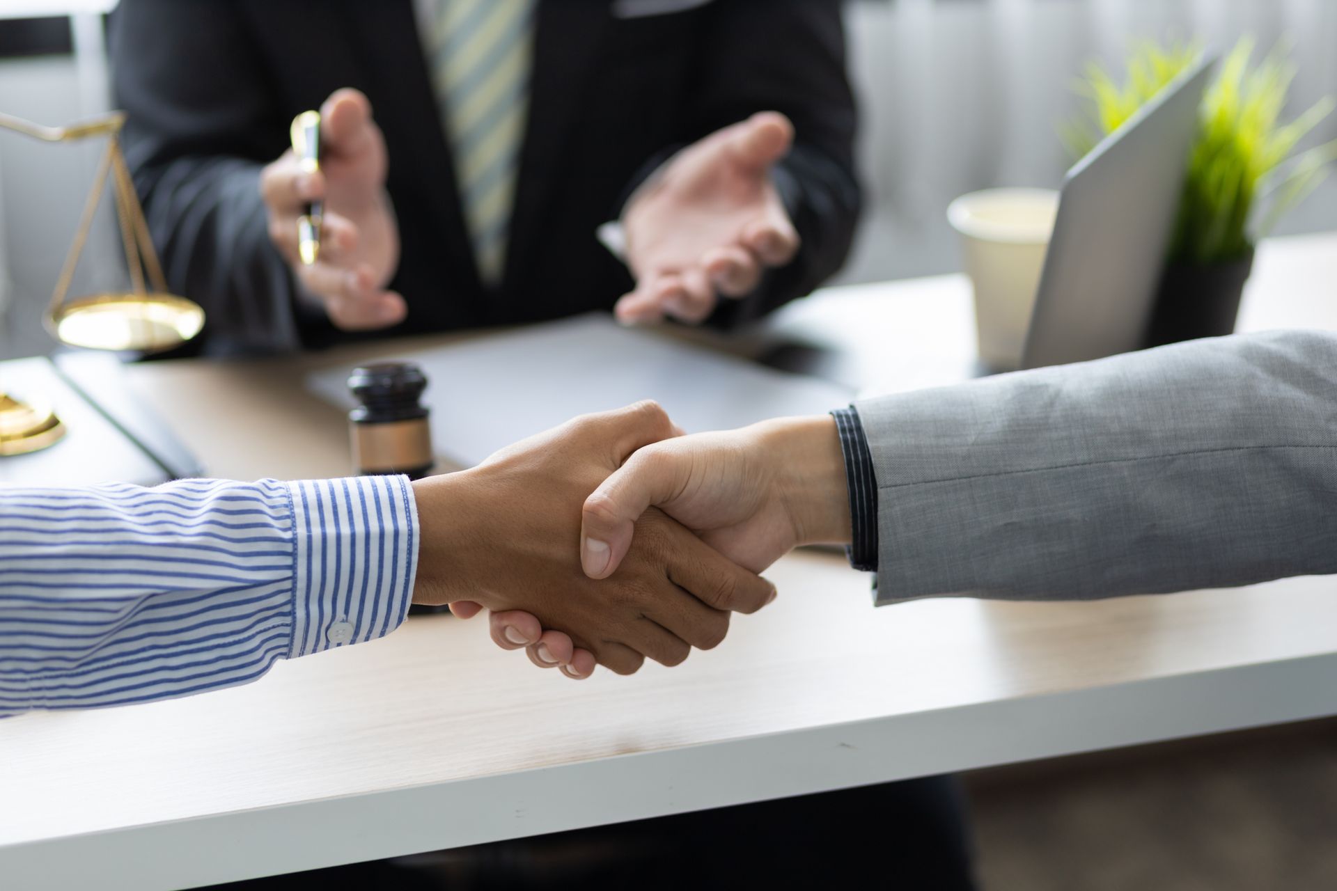 A couple is shaking hands in an office setting with a divorce law attorney, after divorce services.