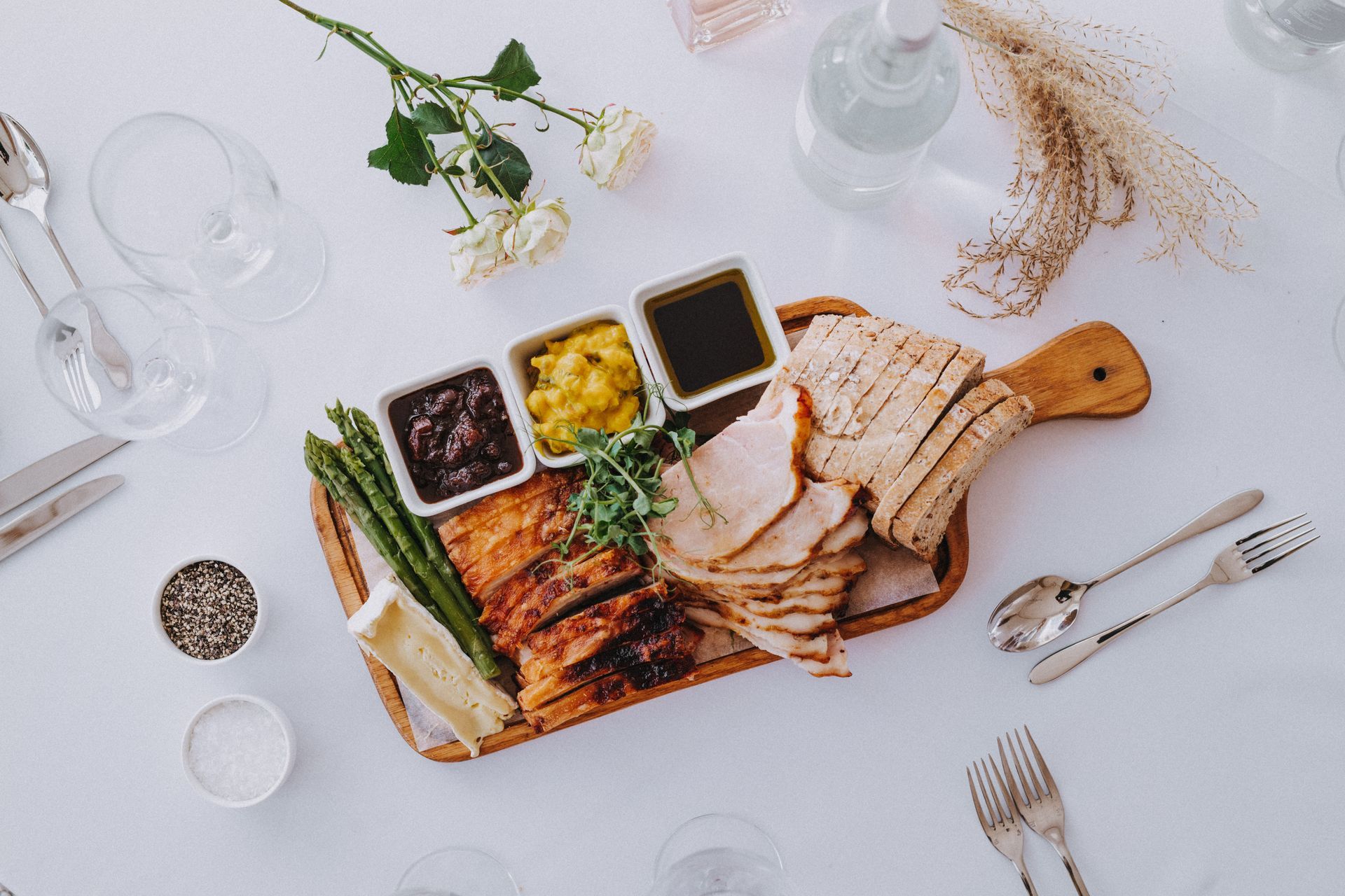 a wooden cutting board filled with food and sauces on a table .
