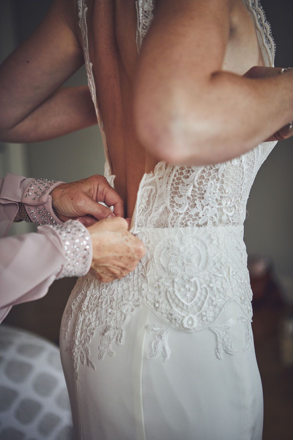 a woman is helping a woman put on her wedding dress .