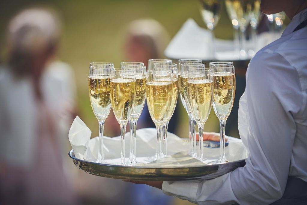 a woman is holding a tray of champagne glasses .