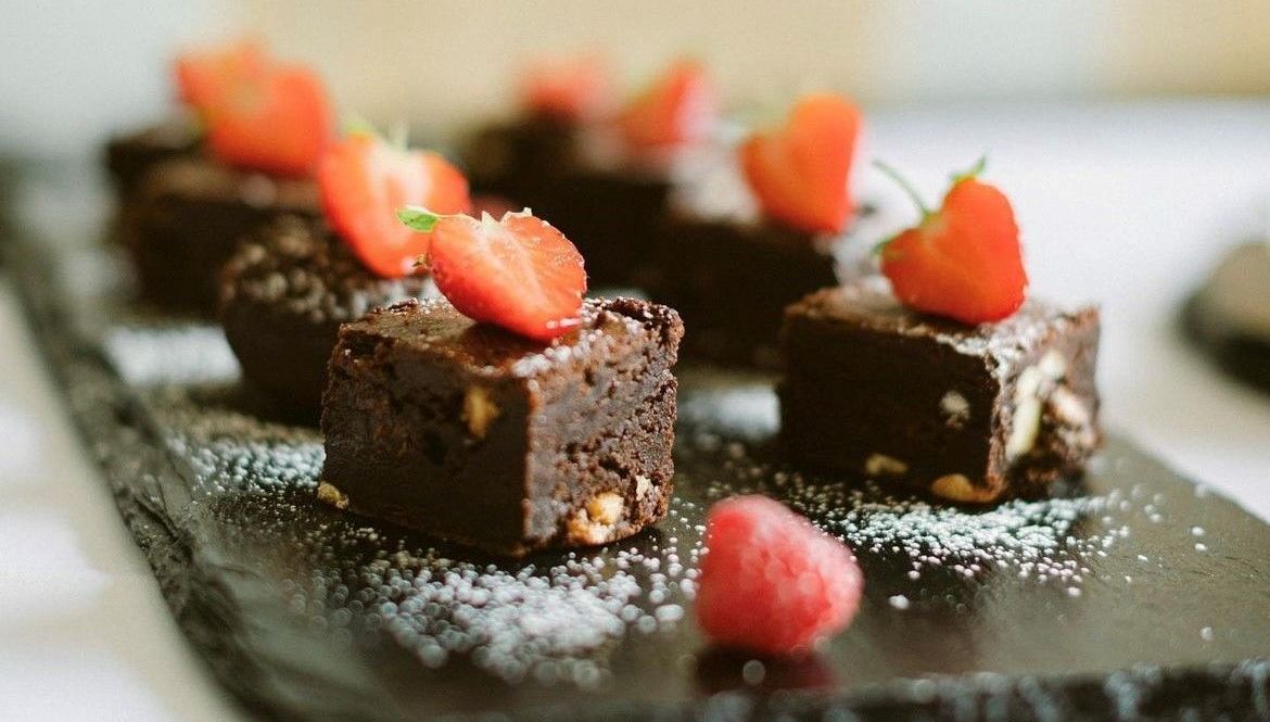 a tray of brownies with strawberries on top on a table .