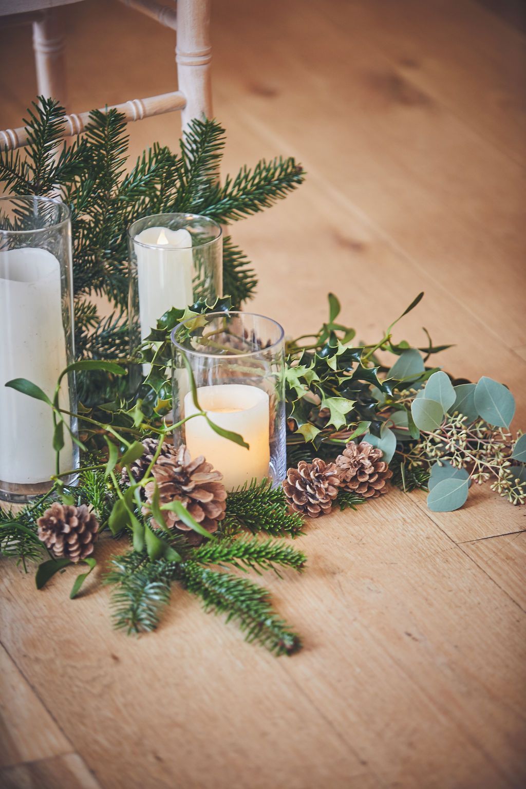 a wooden table topped with candles and pine cones .