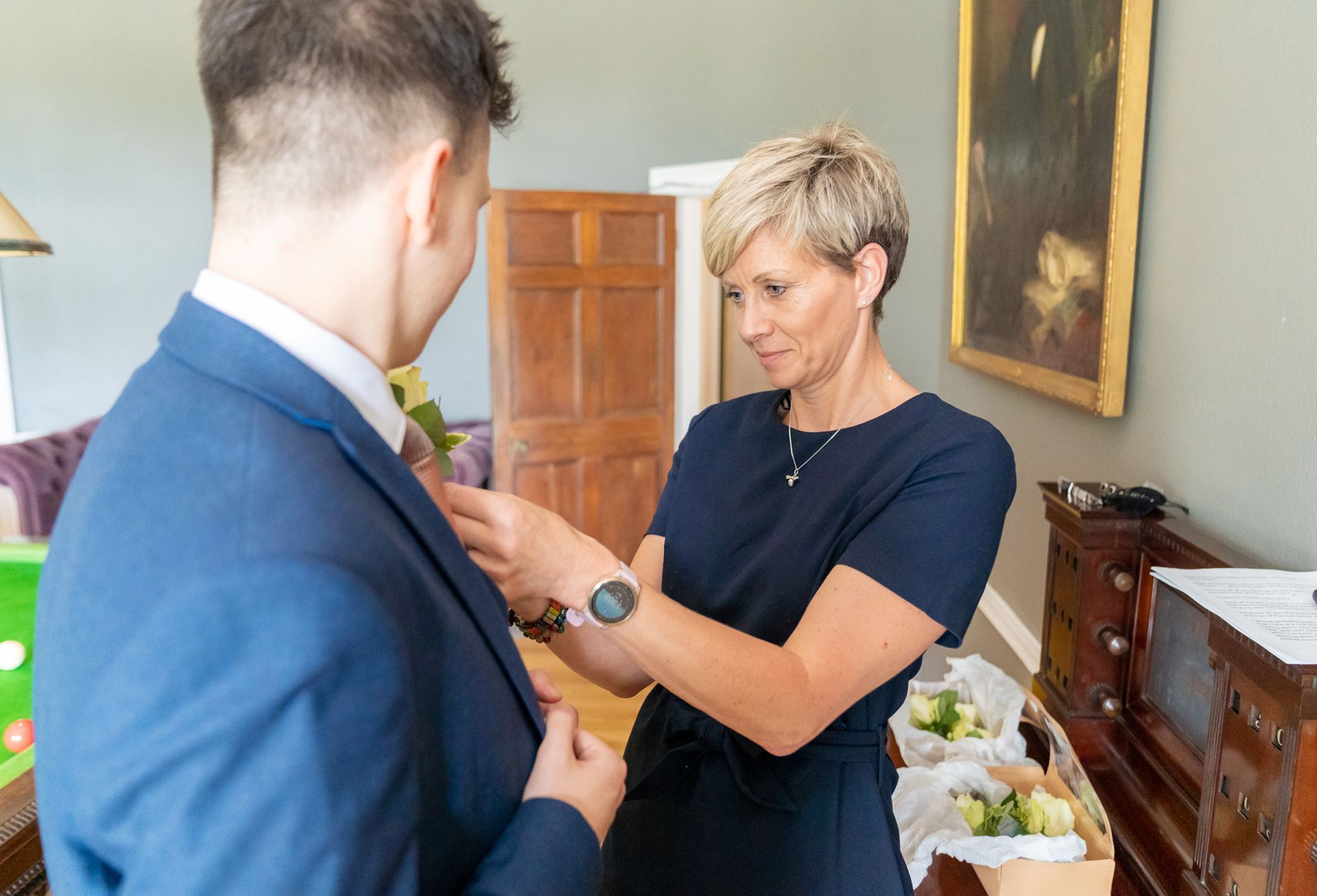 a woman is helping a man get ready for his wedding.