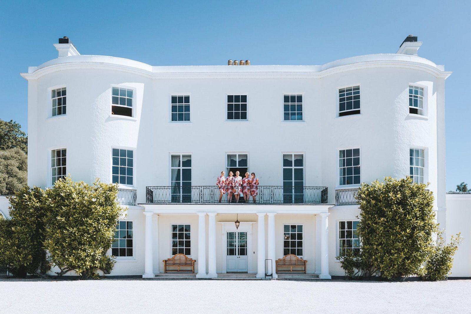a large white house with a balcony and a blue sky in the background