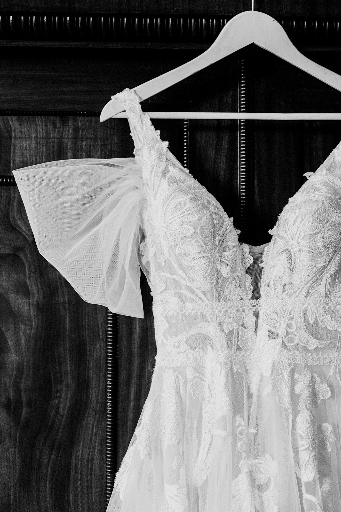 a black and white photo of a wedding dress hanging on a hanger .