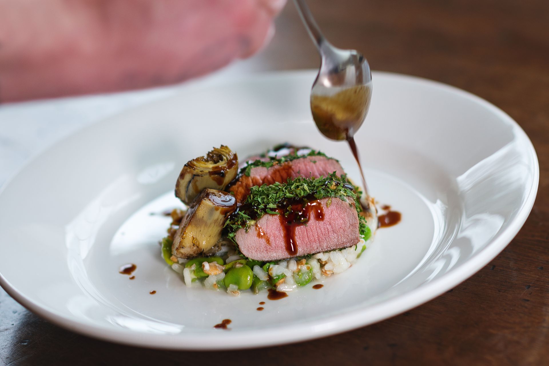 a person is pouring sauce on a plate of food