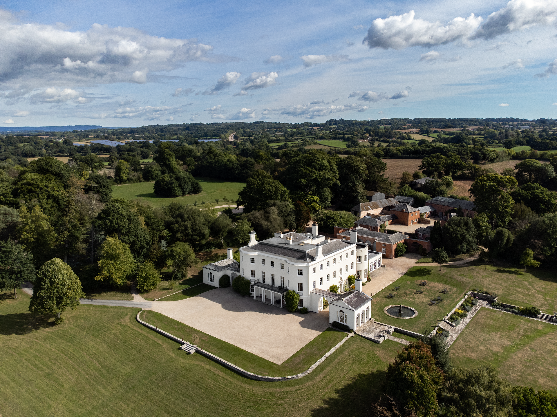 an aerial view of a large white building surrounded by trees and grass. Wedding venue in devon