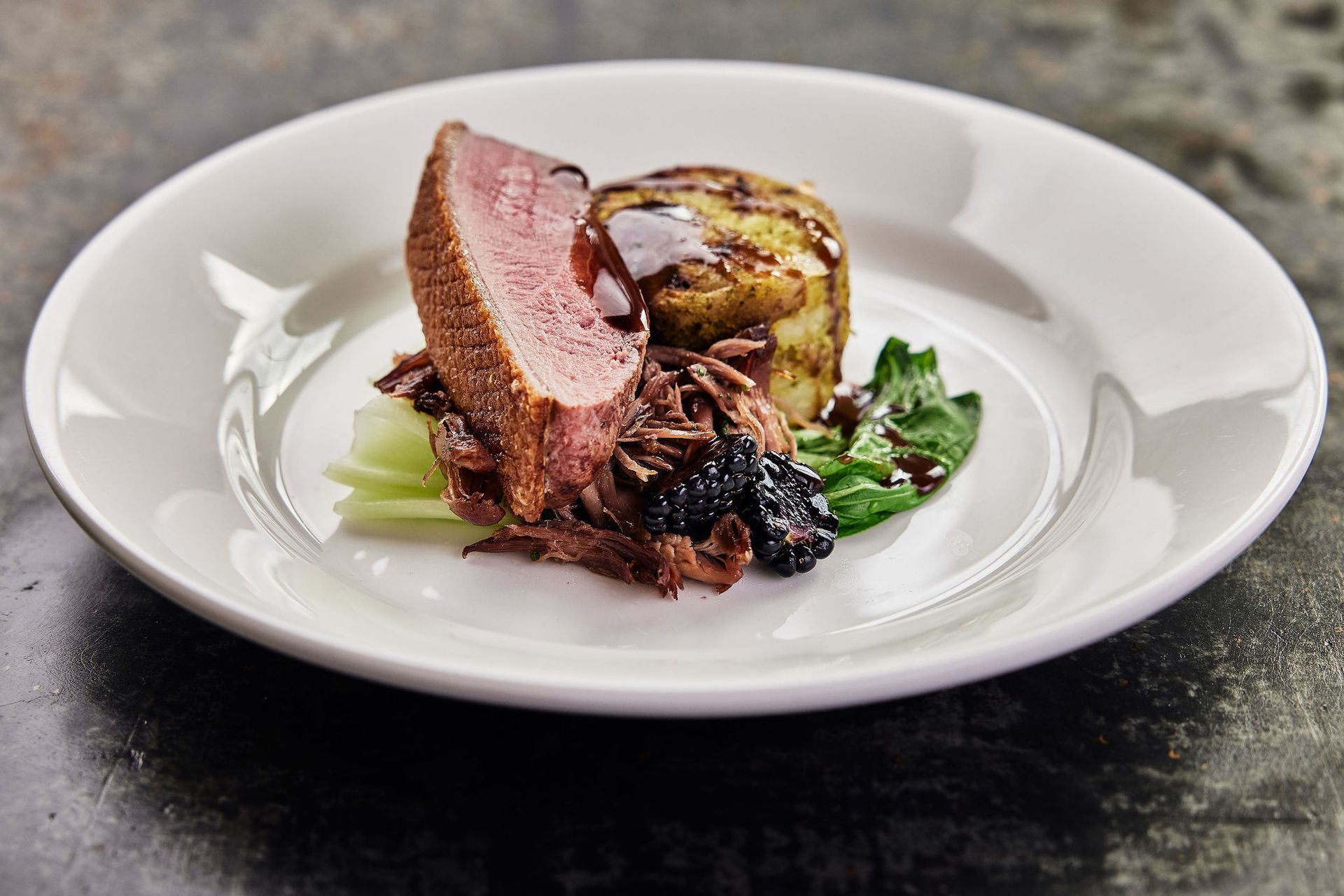 a white plate topped with meat and vegetables on a wooden table .