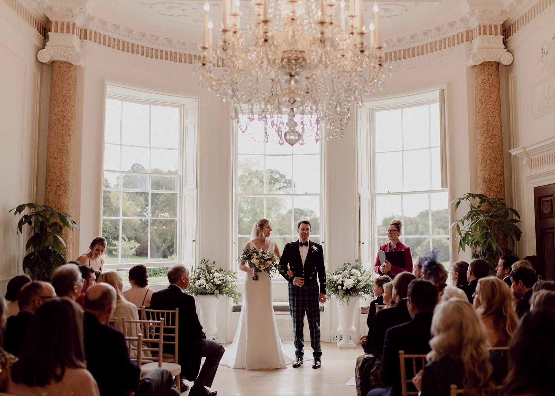 a bride and groom are standing in front of a crowd during their wedding ceremony .