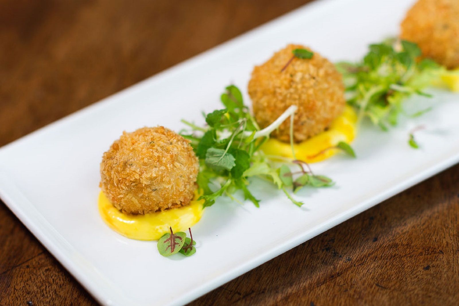 a white plate topped with fried food and sauce on a table .