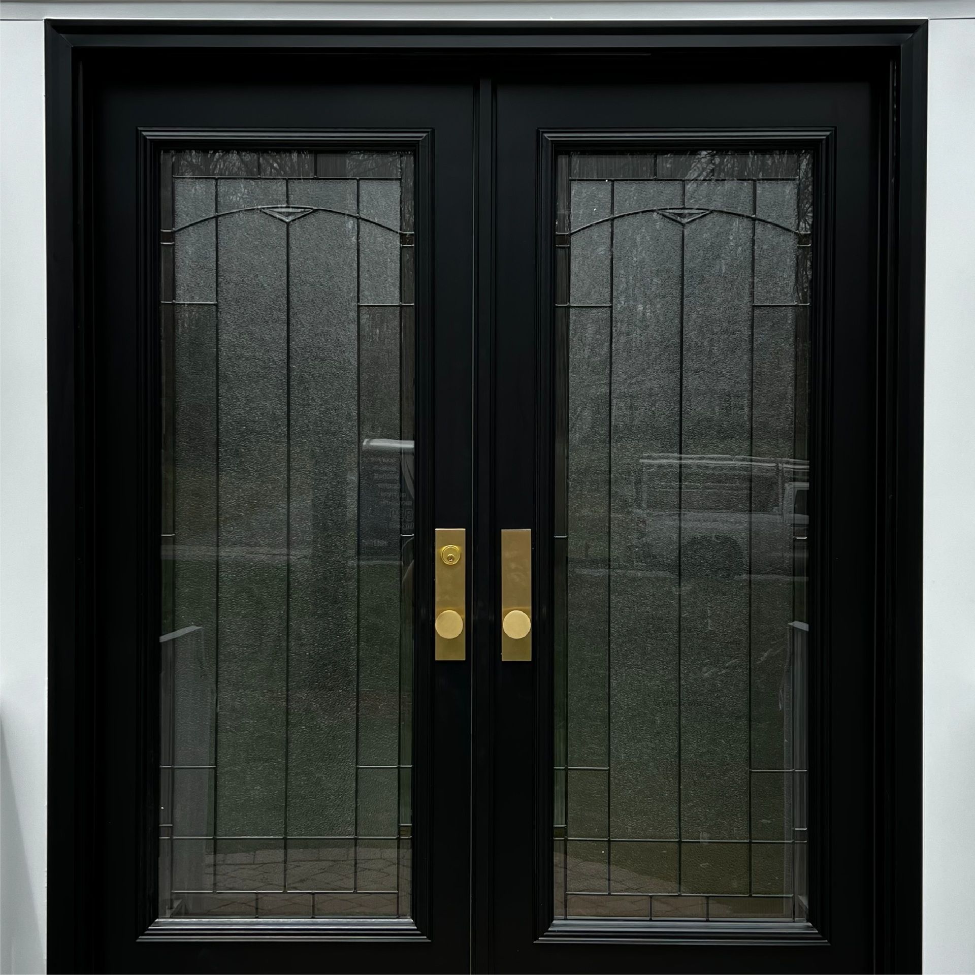 Black double doors with decorative glass panels and gold hardware.