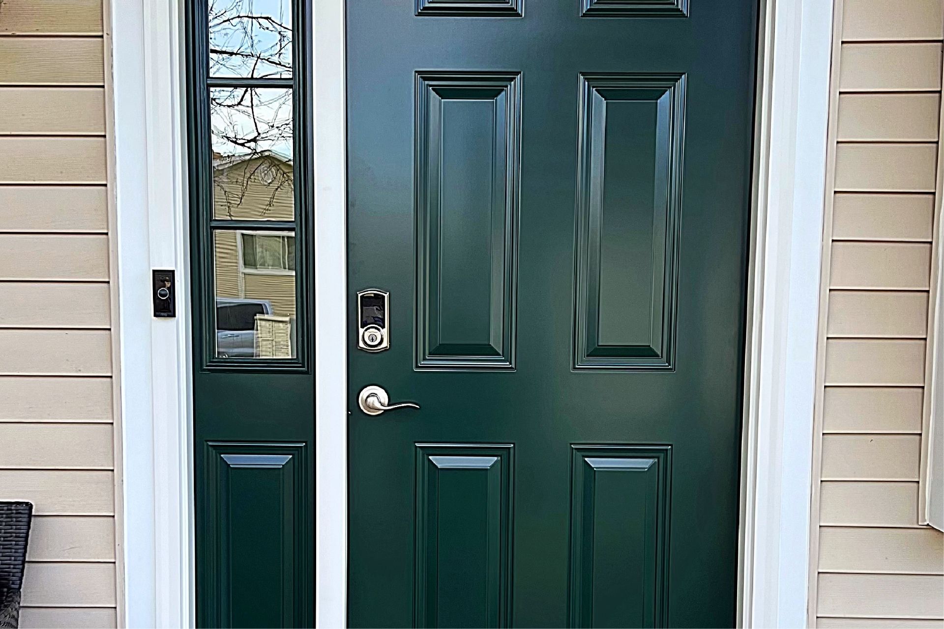 Green front door with sidelight and white trim.