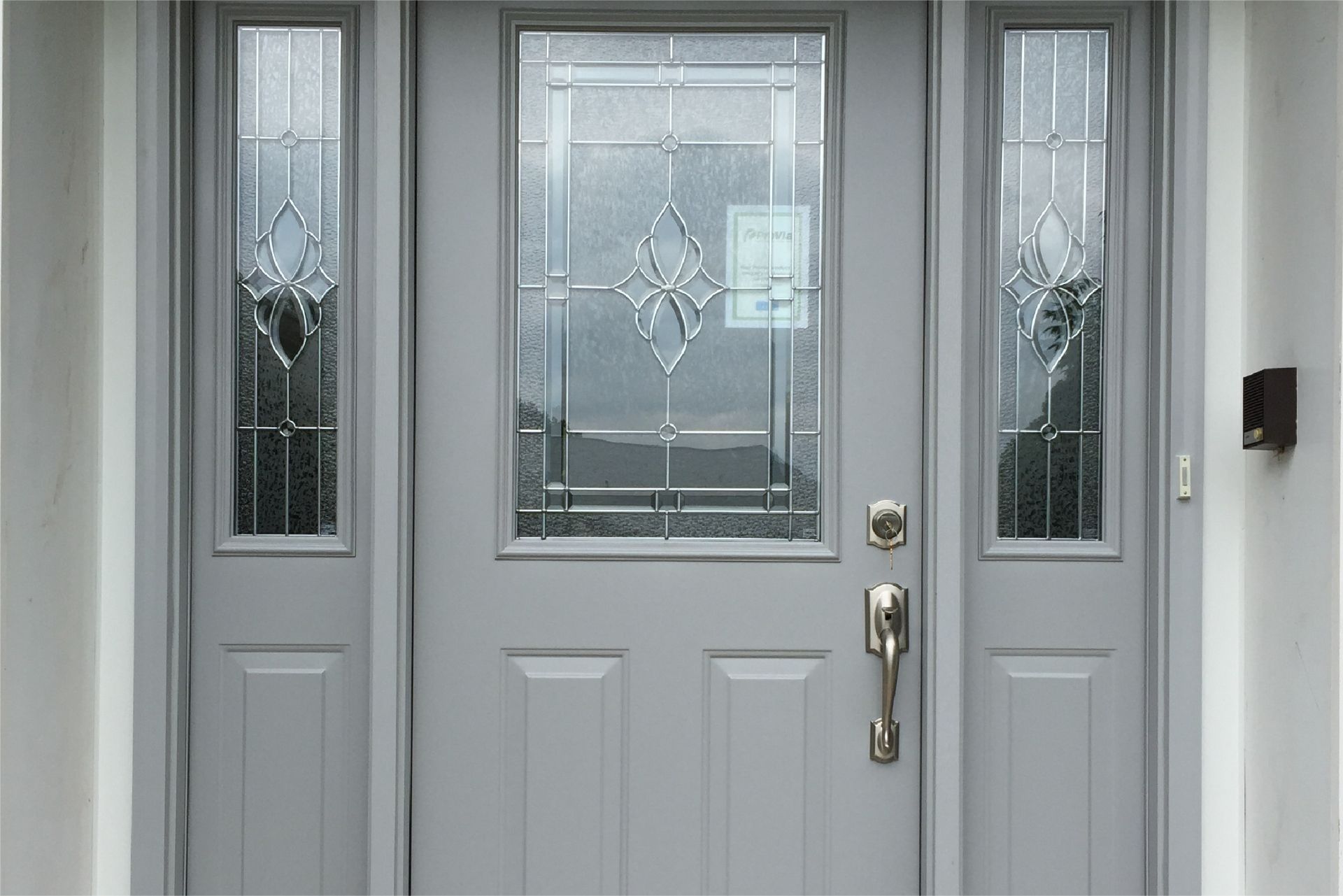 Gray front door with glass panels and sidelights.