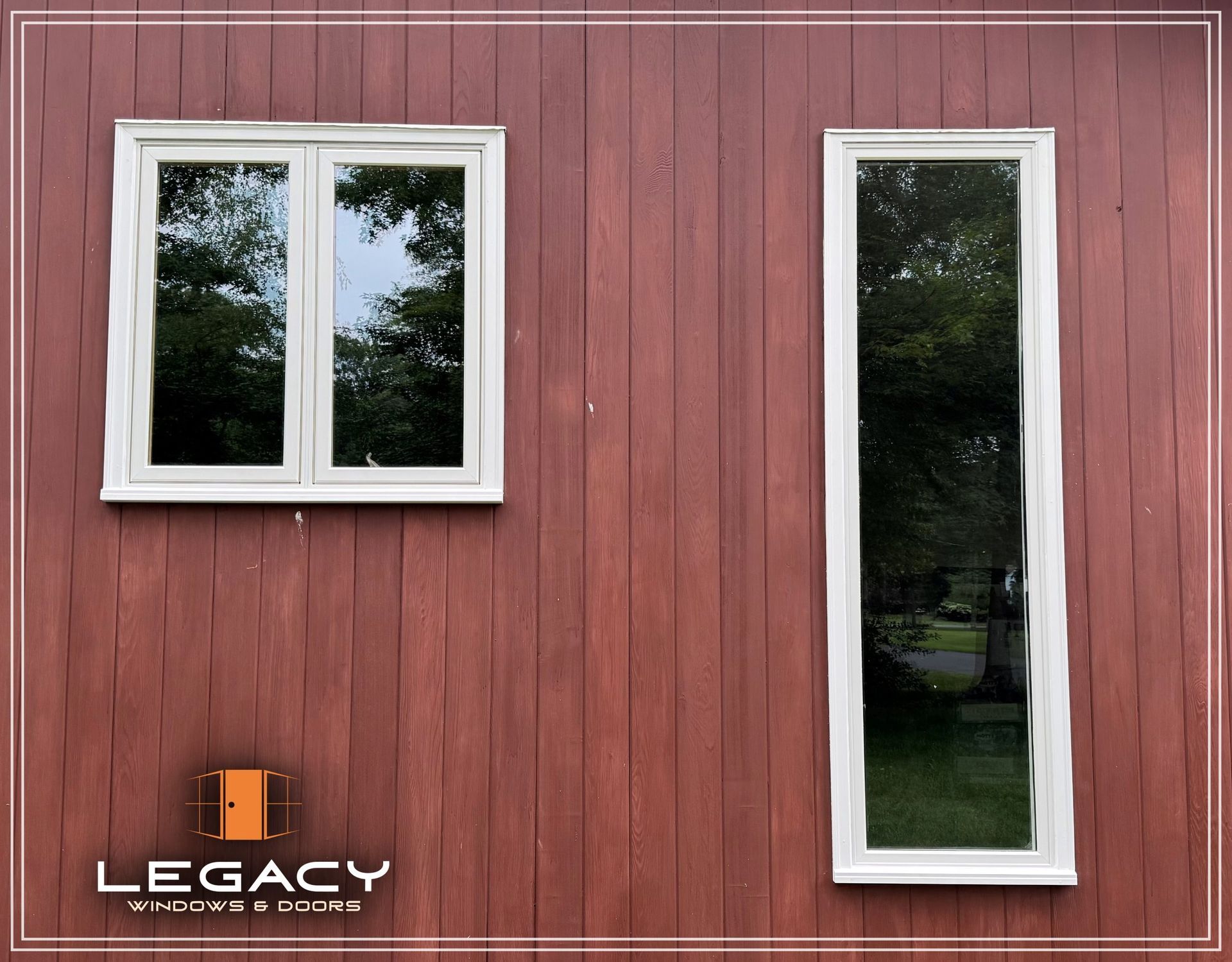 Two white-framed windows on a red-painted wood building. One square, the other tall and narrow.