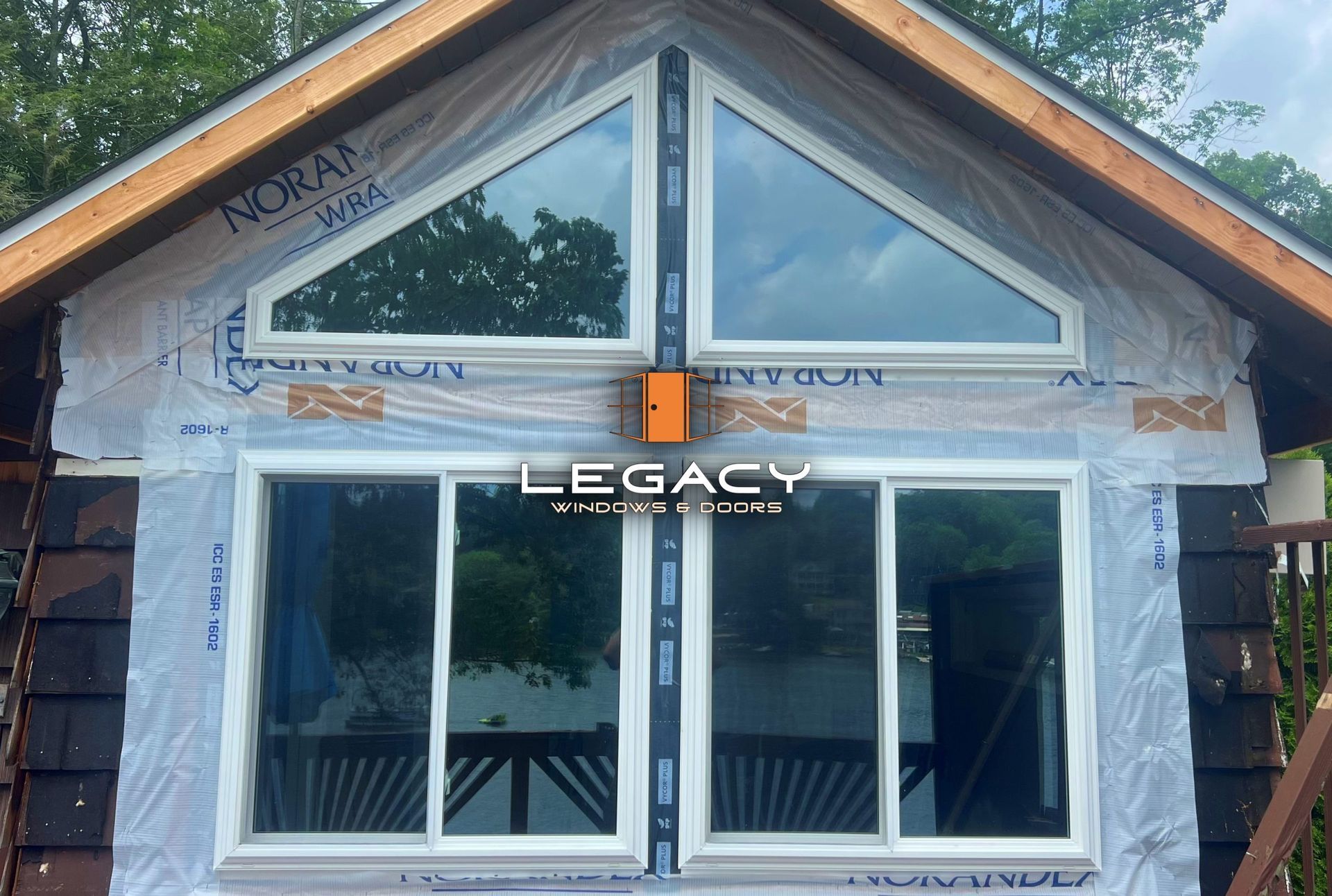 Exterior of a house with two sliding windows and a triangular window. Windows are white-framed.