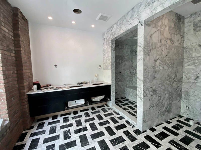 A bathroom with a walk in shower and a black and white tile floor.