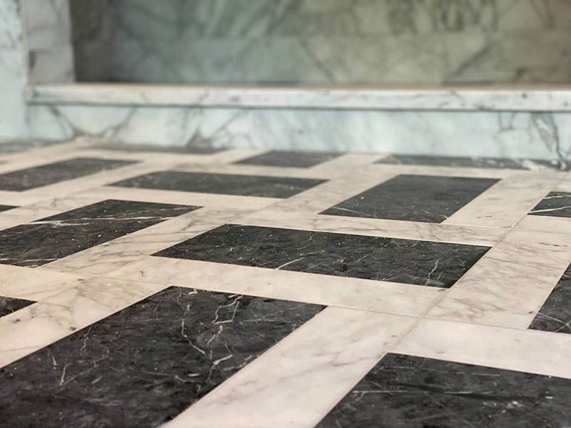 A black and white checkered marble floor with stairs in the background