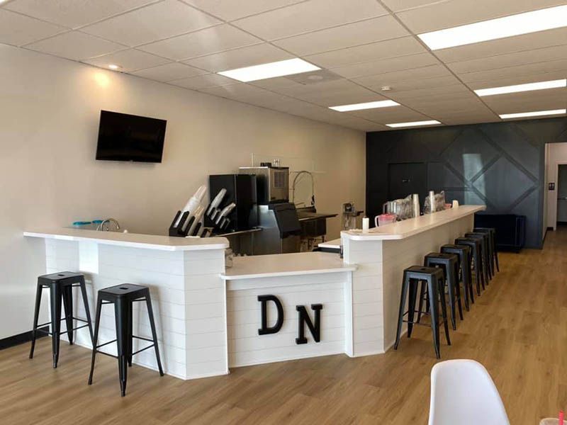 The inside of a restaurant with a long counter and stools.