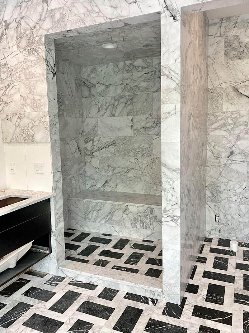 A bathroom with marble walls and a black and white tile floor.