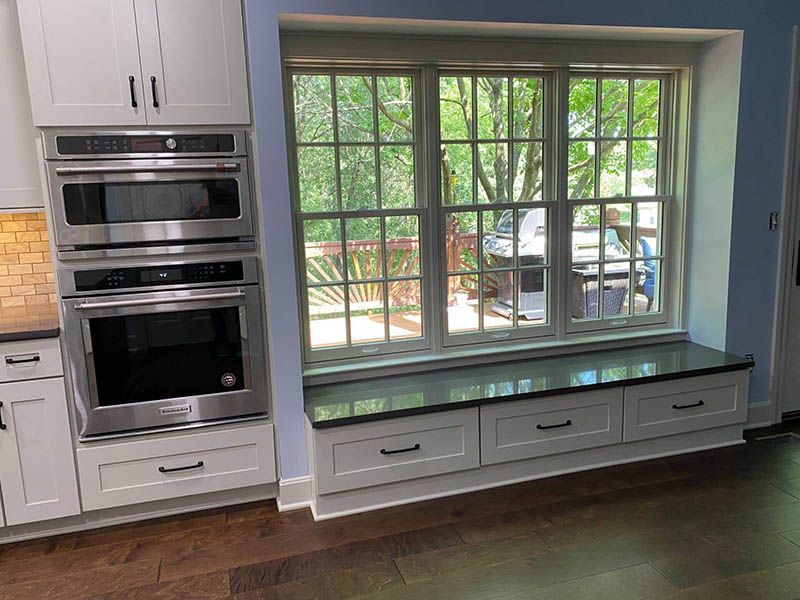 A kitchen with stainless steel appliances and a window seat.