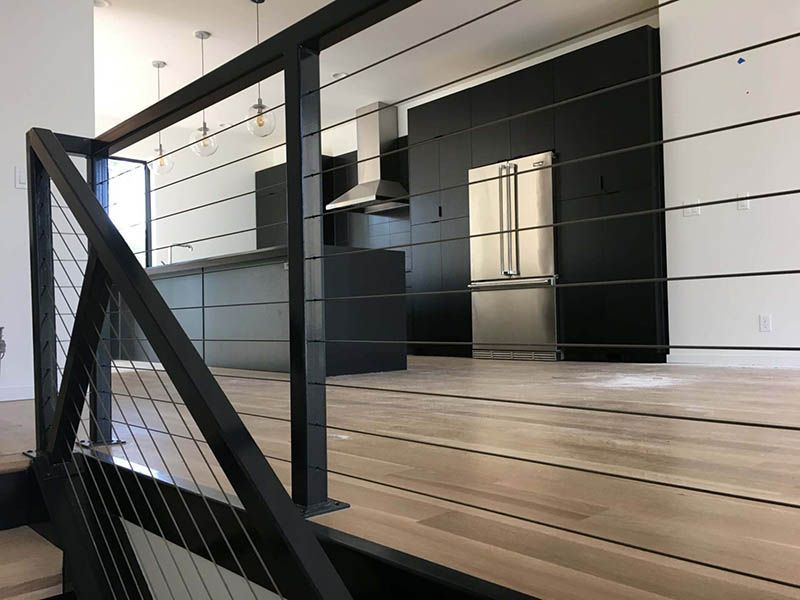 A staircase leading to a kitchen with a stainless steel refrigerator.