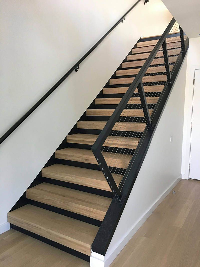 A wooden staircase with a metal railing in a room.